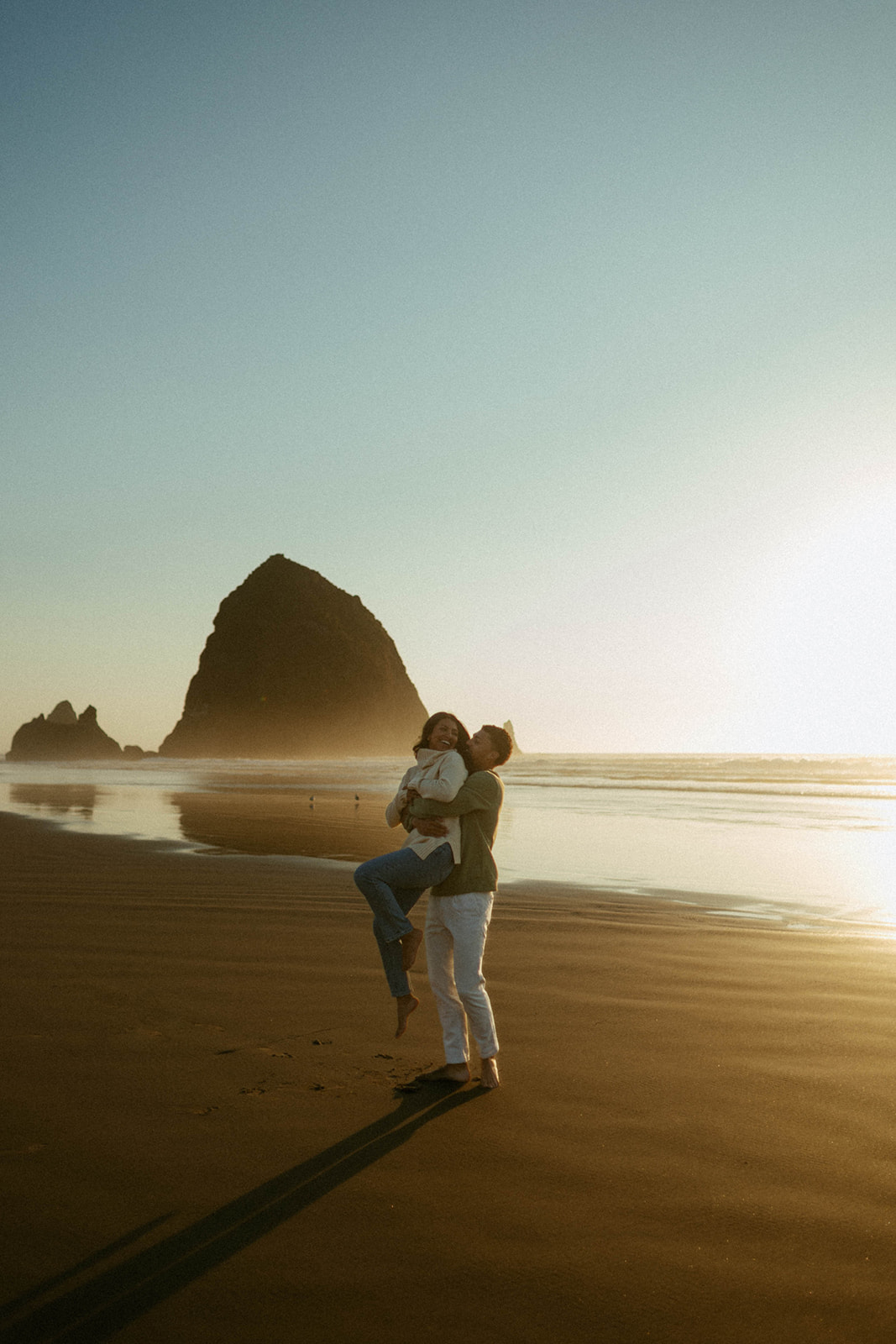 Couple embraces while enjoying a sunset on Cannon Beach on the Oregon Coast.