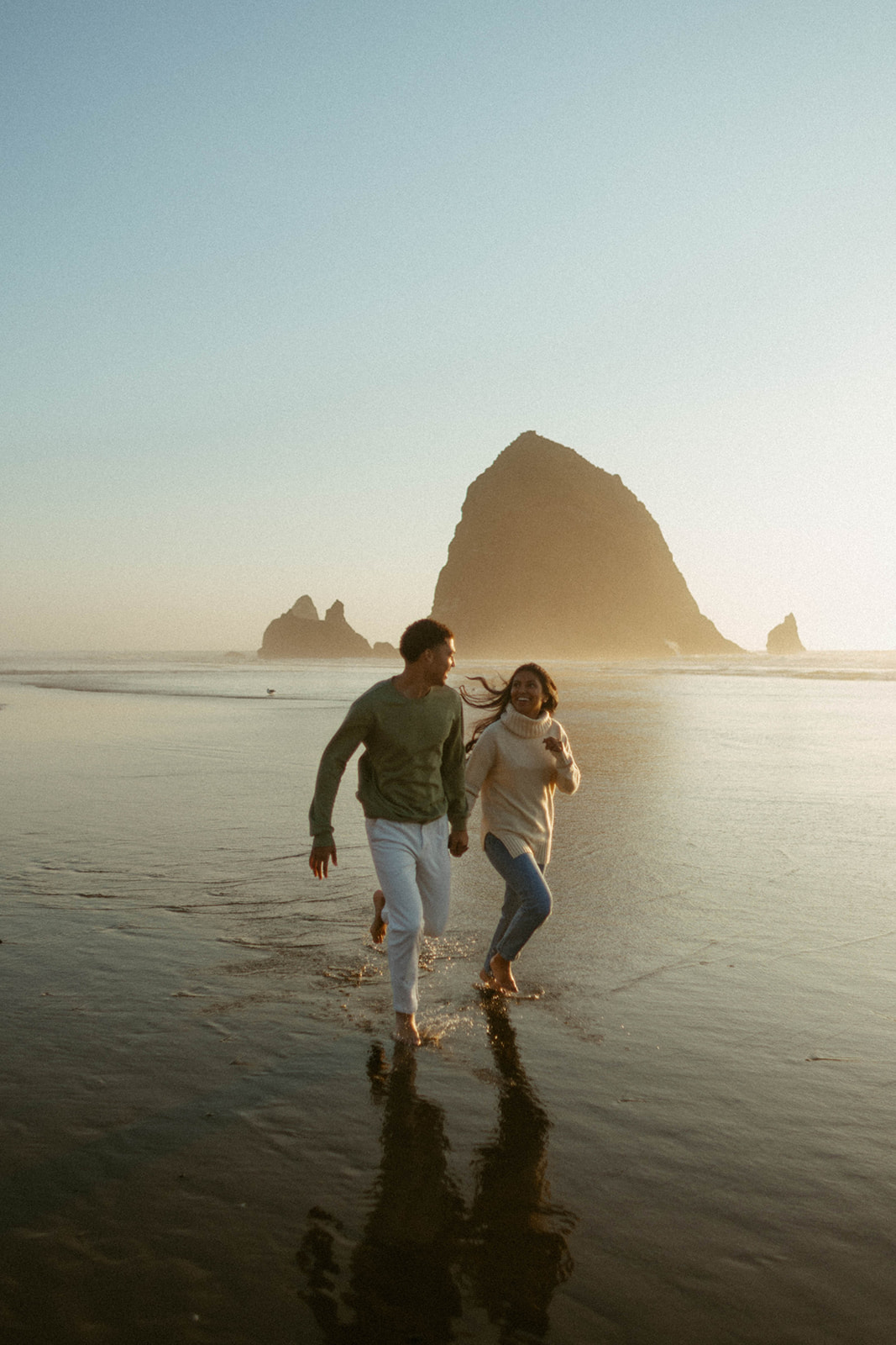 Couple runs together down Cannon Beach on the Oregon Coast.