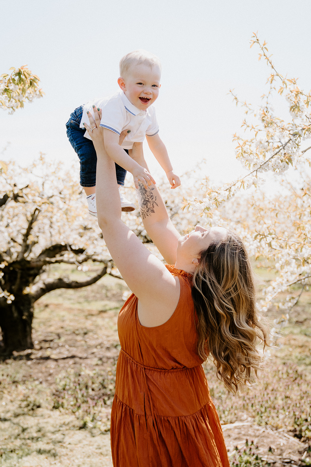 Mom holding toddler up with both arms above her head.