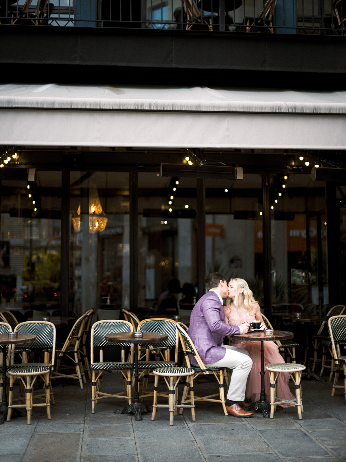 Couple kissing outside Paris cafe.