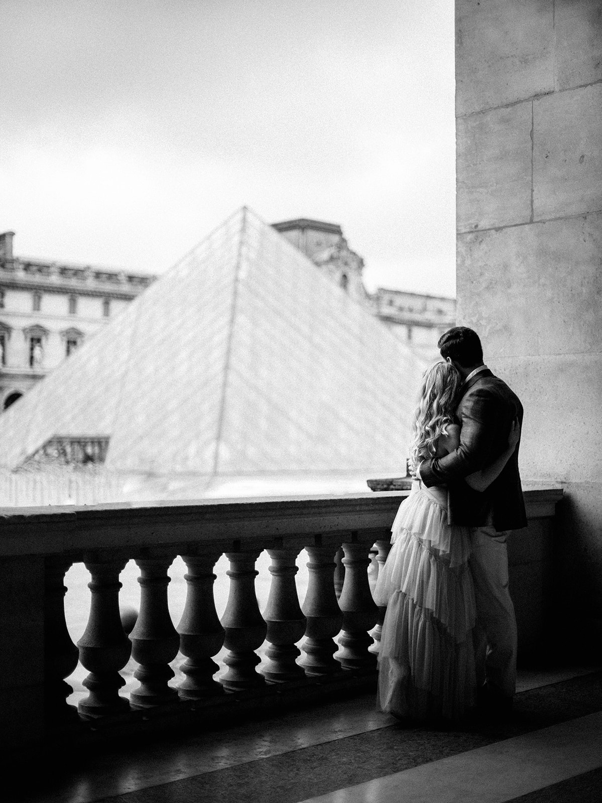 Couple looks out towards the Louvre.