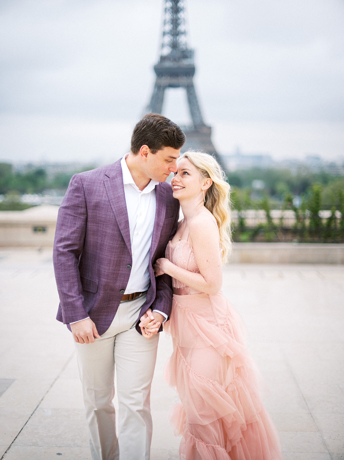 Couple nestled close to one another with Eiffel Tower in the background.