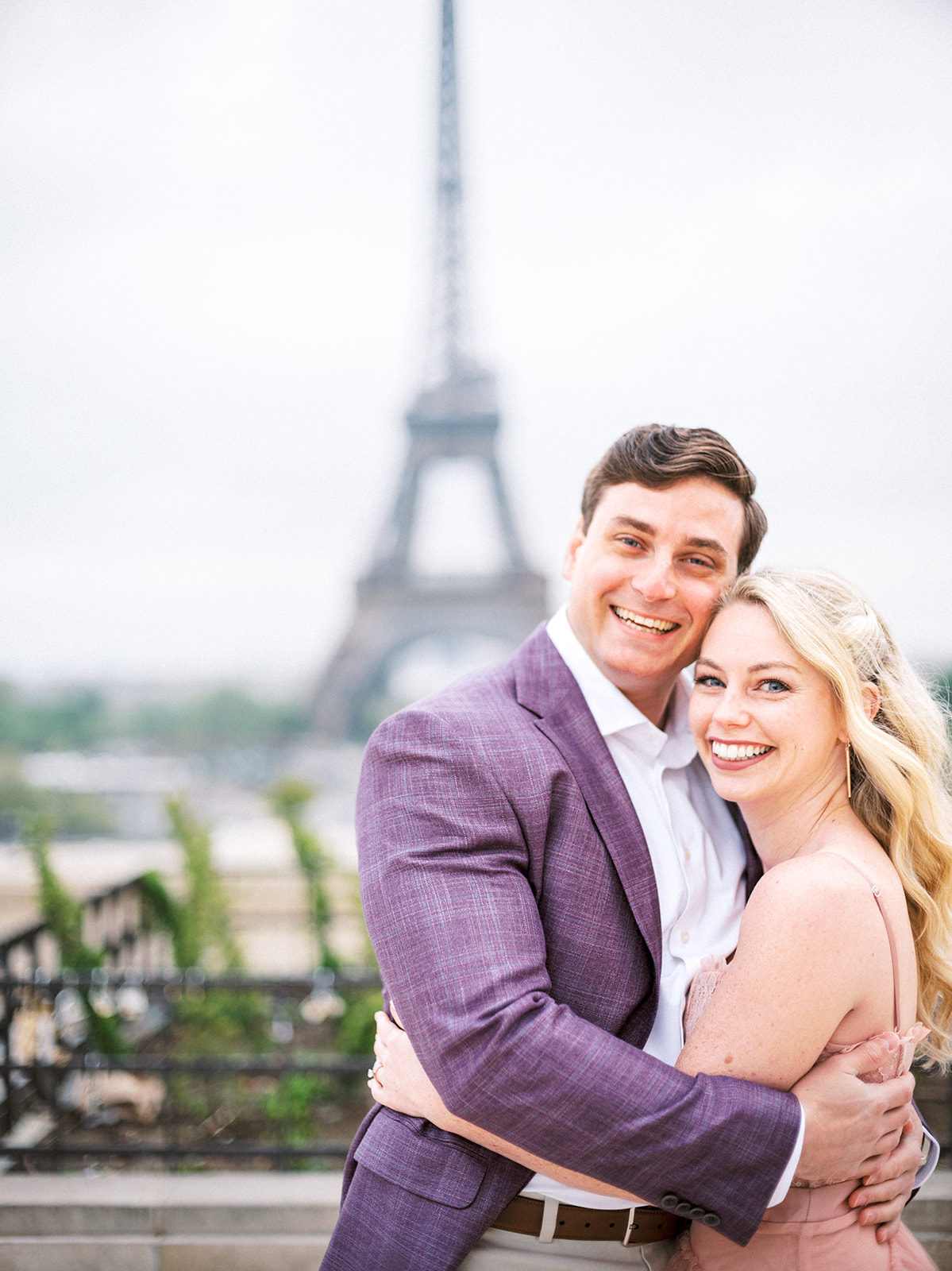 Couple smiling looking at camera with Eiffel Tower in the background.