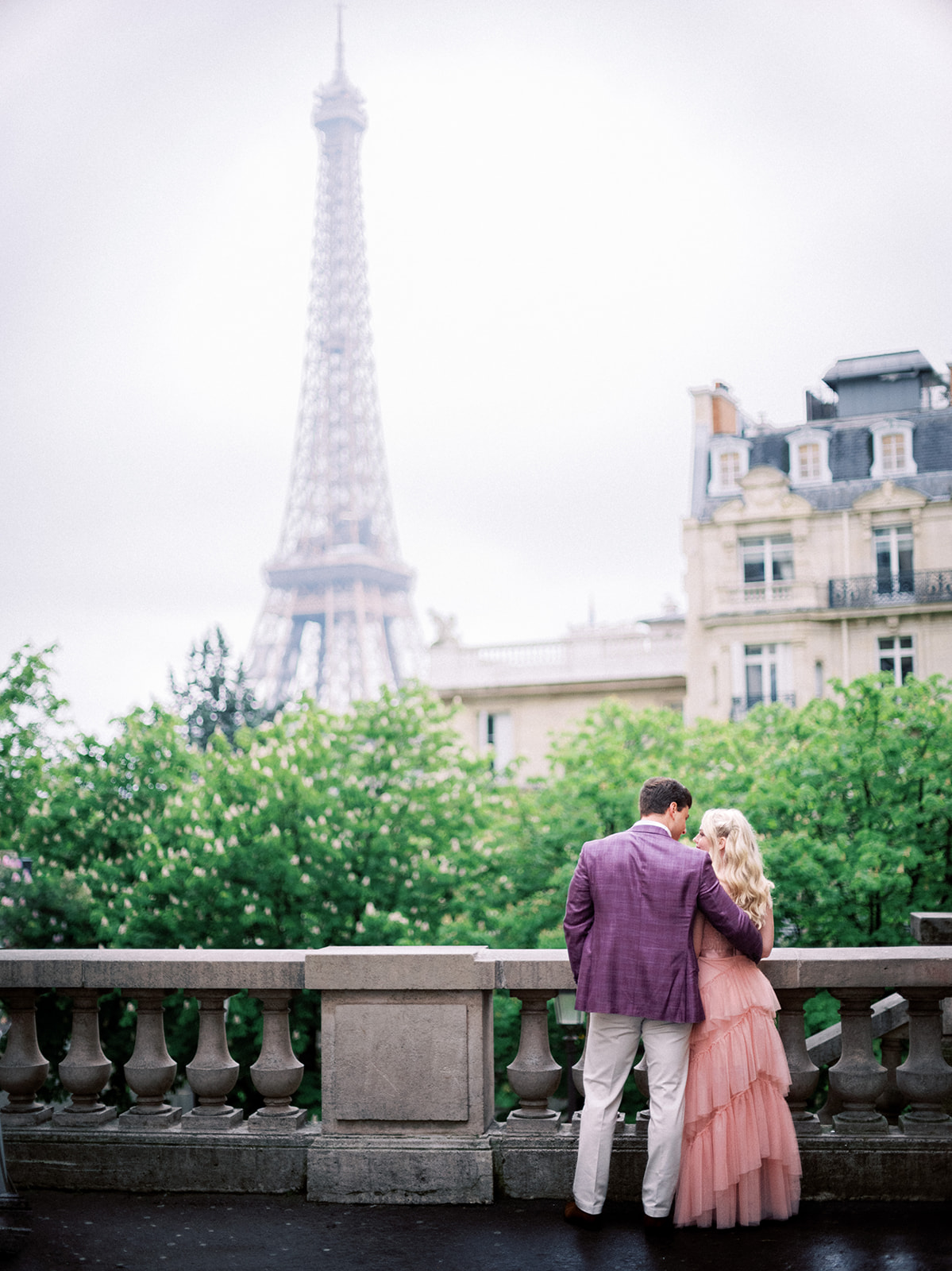 Couple standing backs to the camera with Eiffel Tower in background.