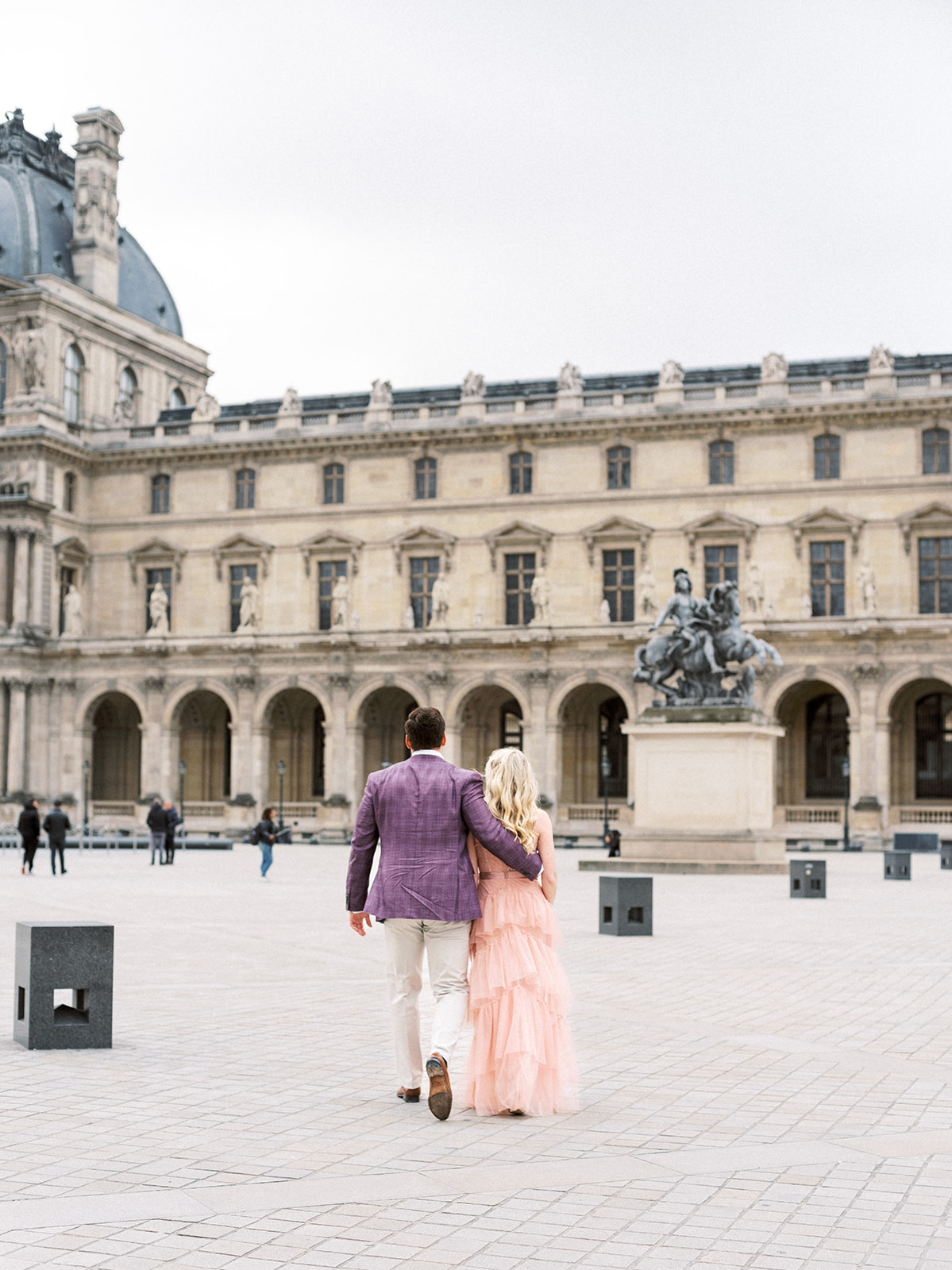 Couple walking towards Louvre during Paris engagement session.