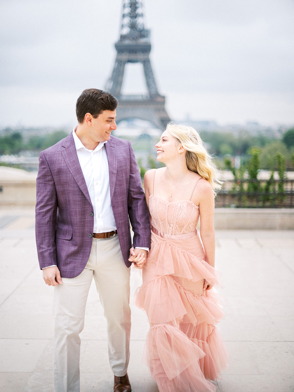 Couple walks along Eiffel Tower.