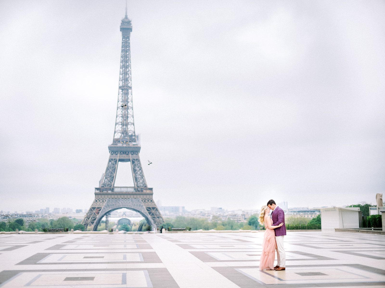 Far away shot of couple near Eiffel Tower during Paris engagement session.