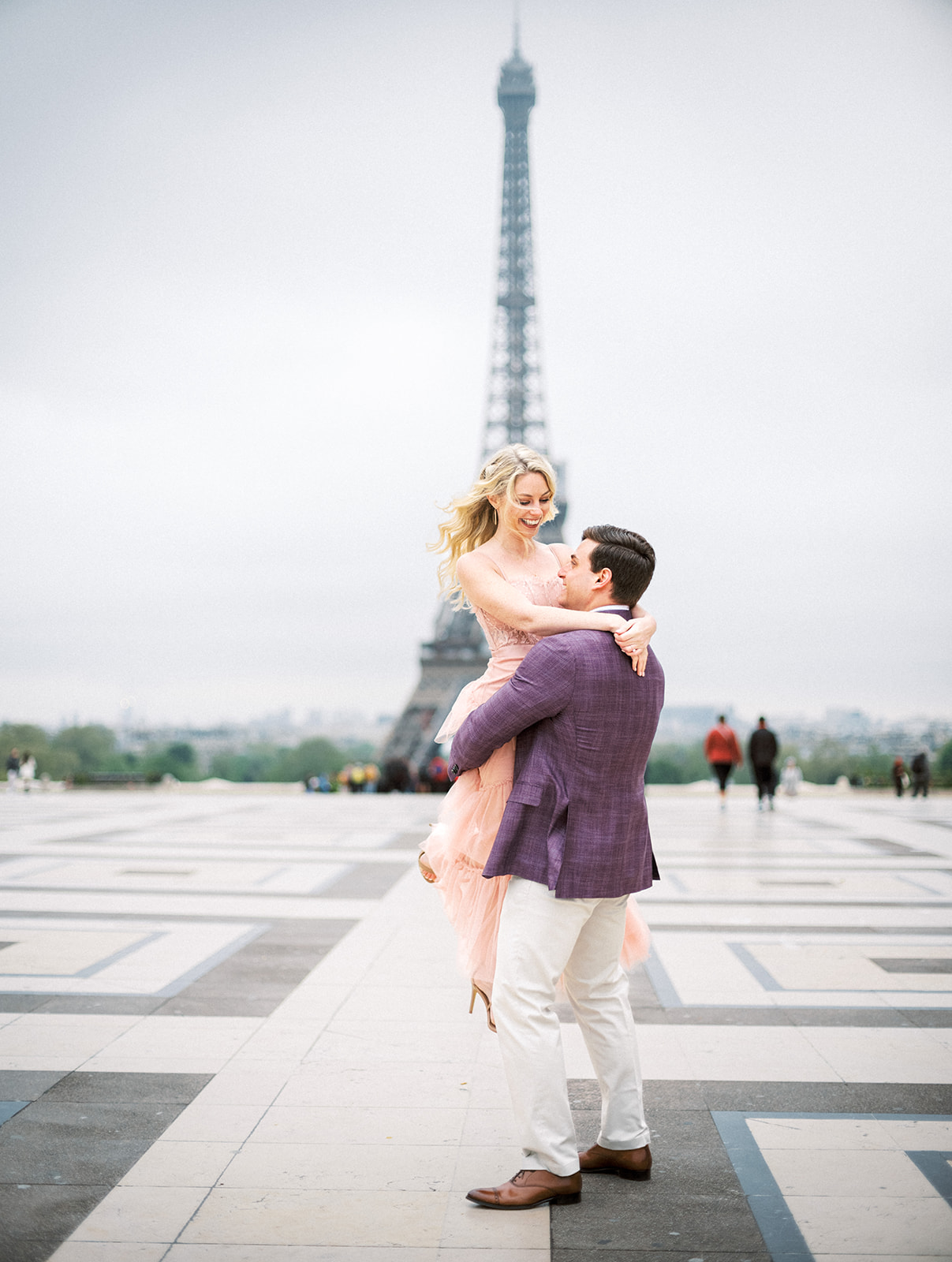 Man picks up woman in front of Eiffel Tower.