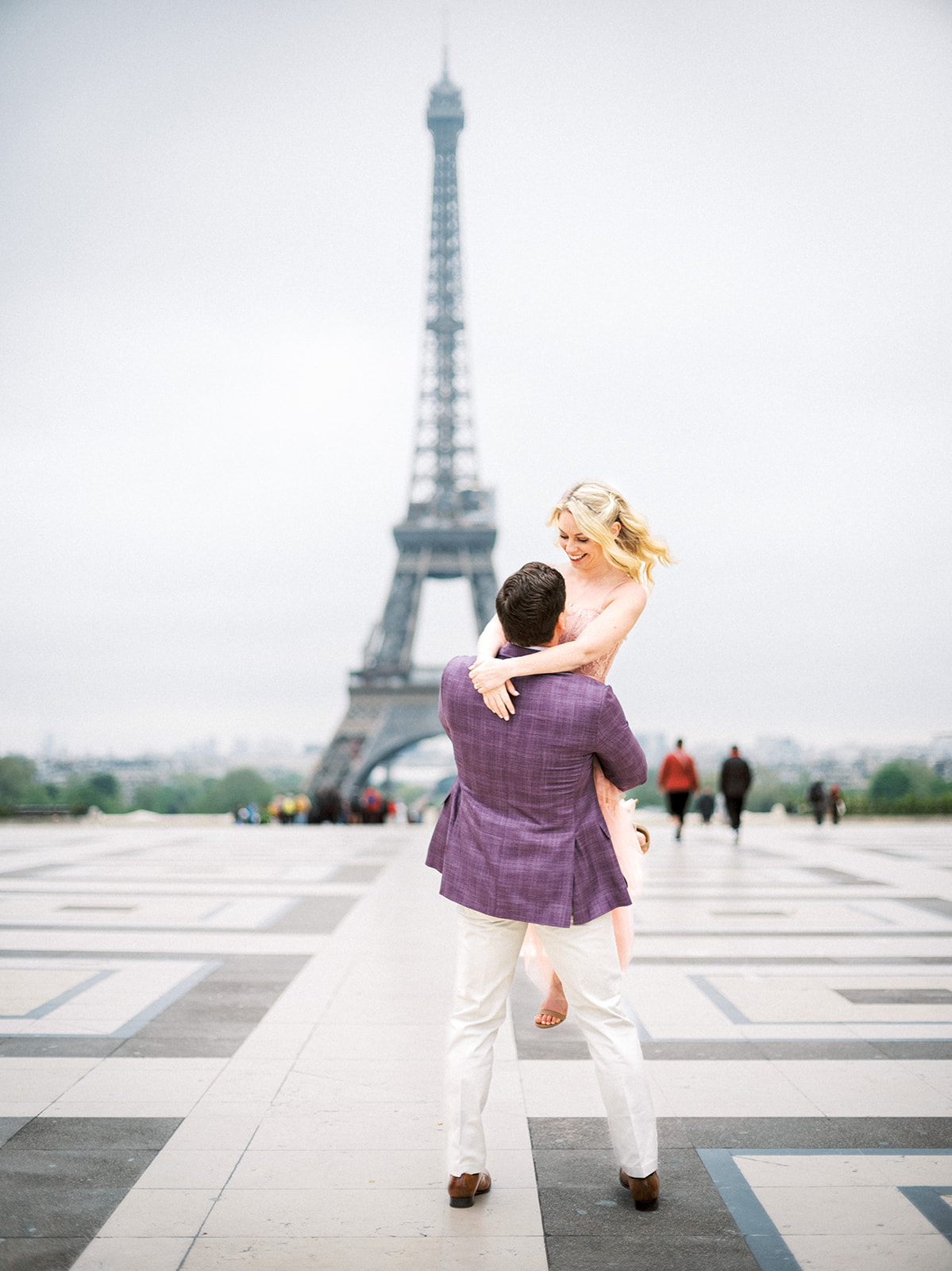 Man spinning woman in front of the Eiffel Tower.