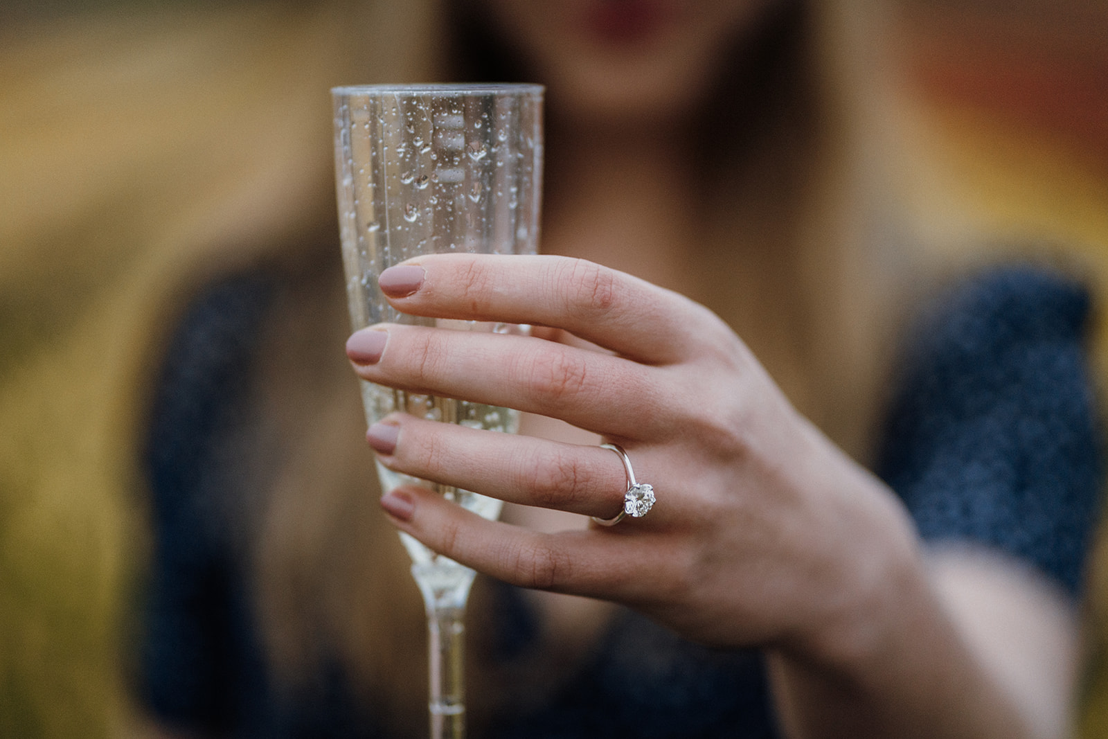 Girl holds out a glass showing off her ring.
