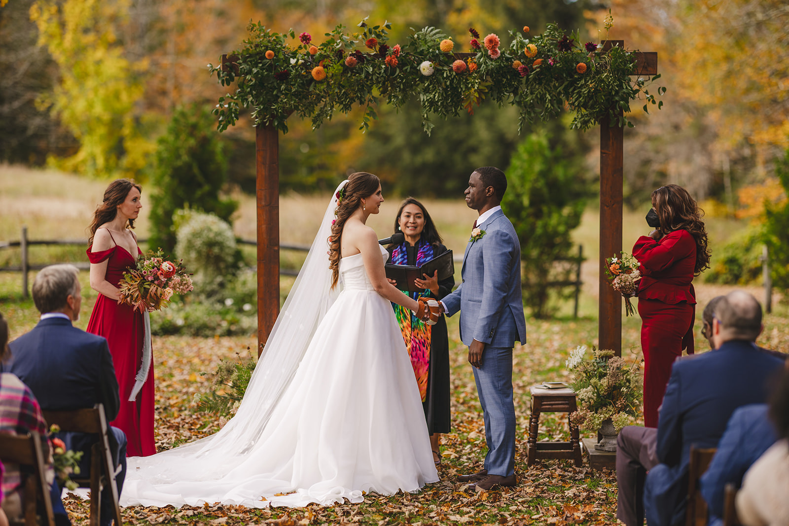a bride and groom hold hands during their outdoor  fall wedding 