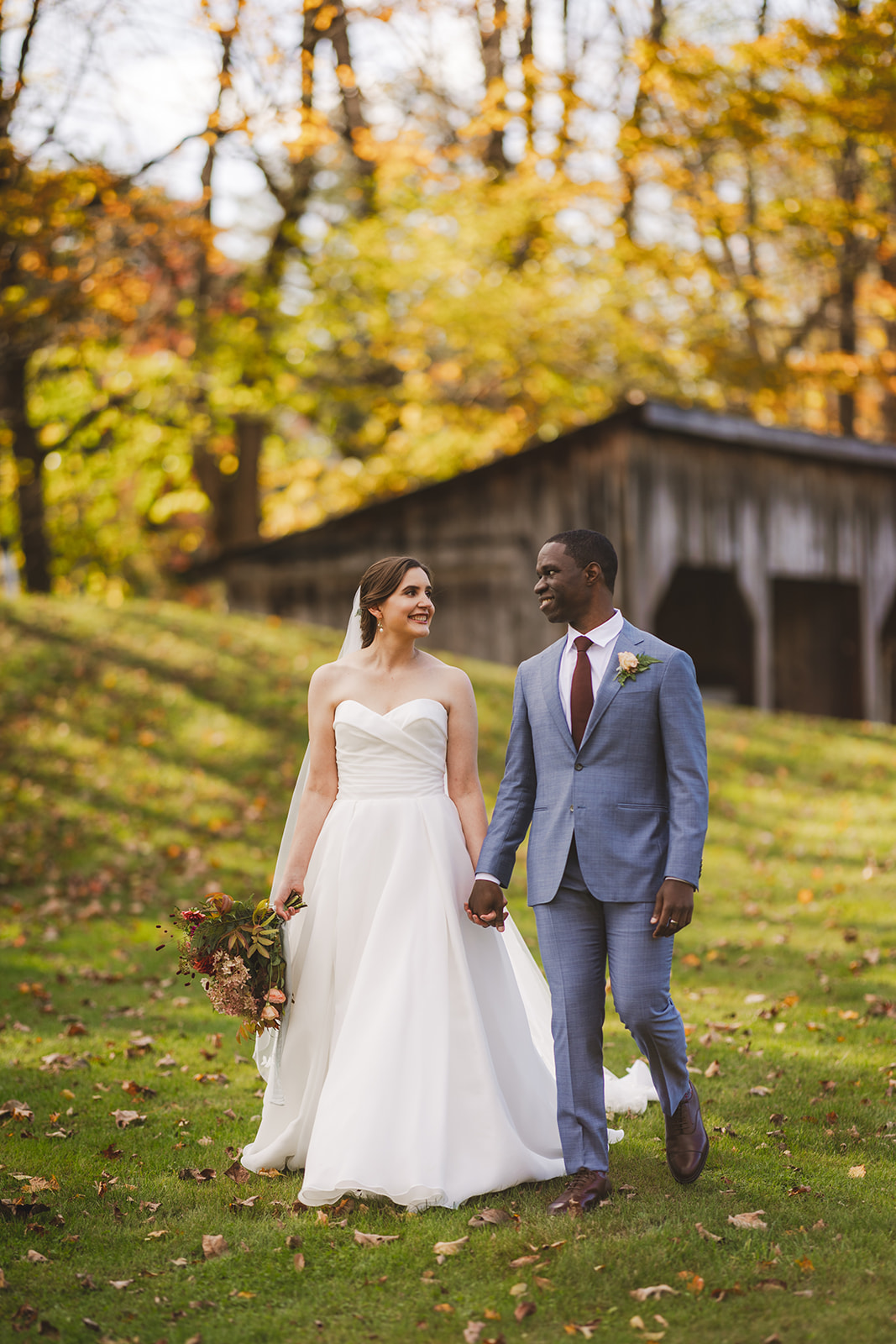 a bride and groom pose together in front of fall color trees at the historic Grafton Inn in Grafton Vermont