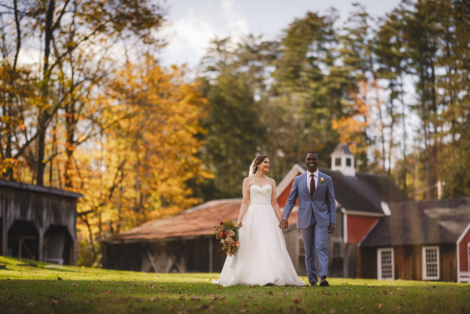 a bride and groom pose together in front of fall color trees at the historic Grafton Inn in Grafton Vermont