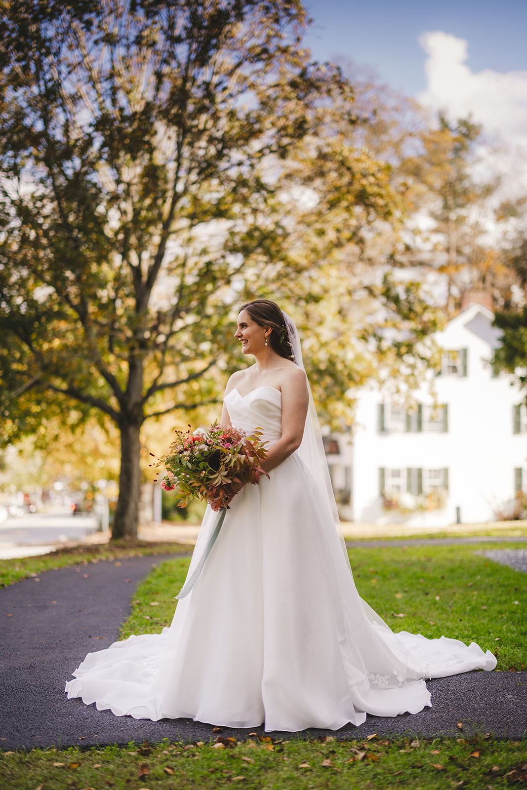 a bride in a white gown holding her flowers poses in front of the historic Grafton Inn in Grafton Vermont