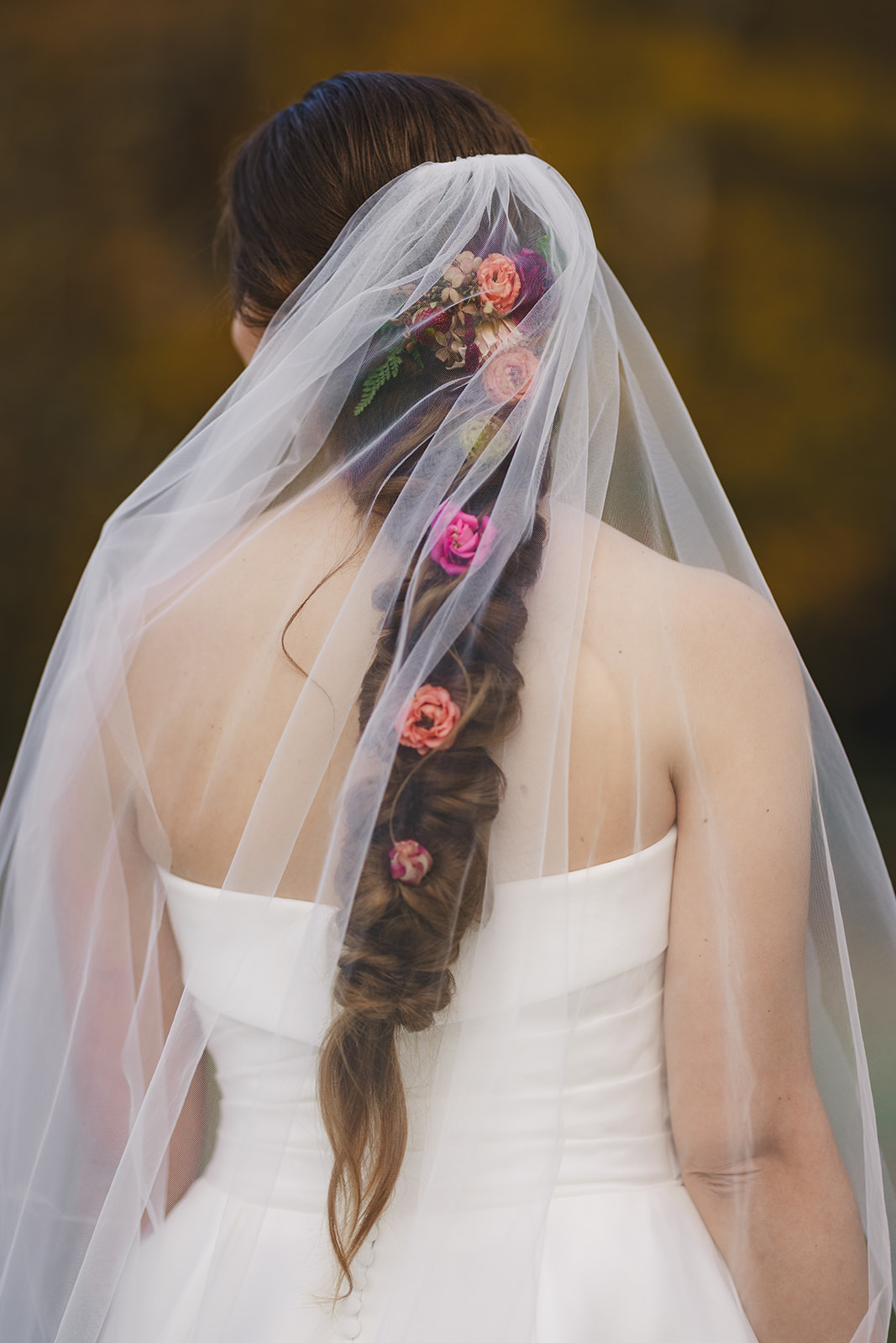 a close up of a bride's braided hair with flowers and veil