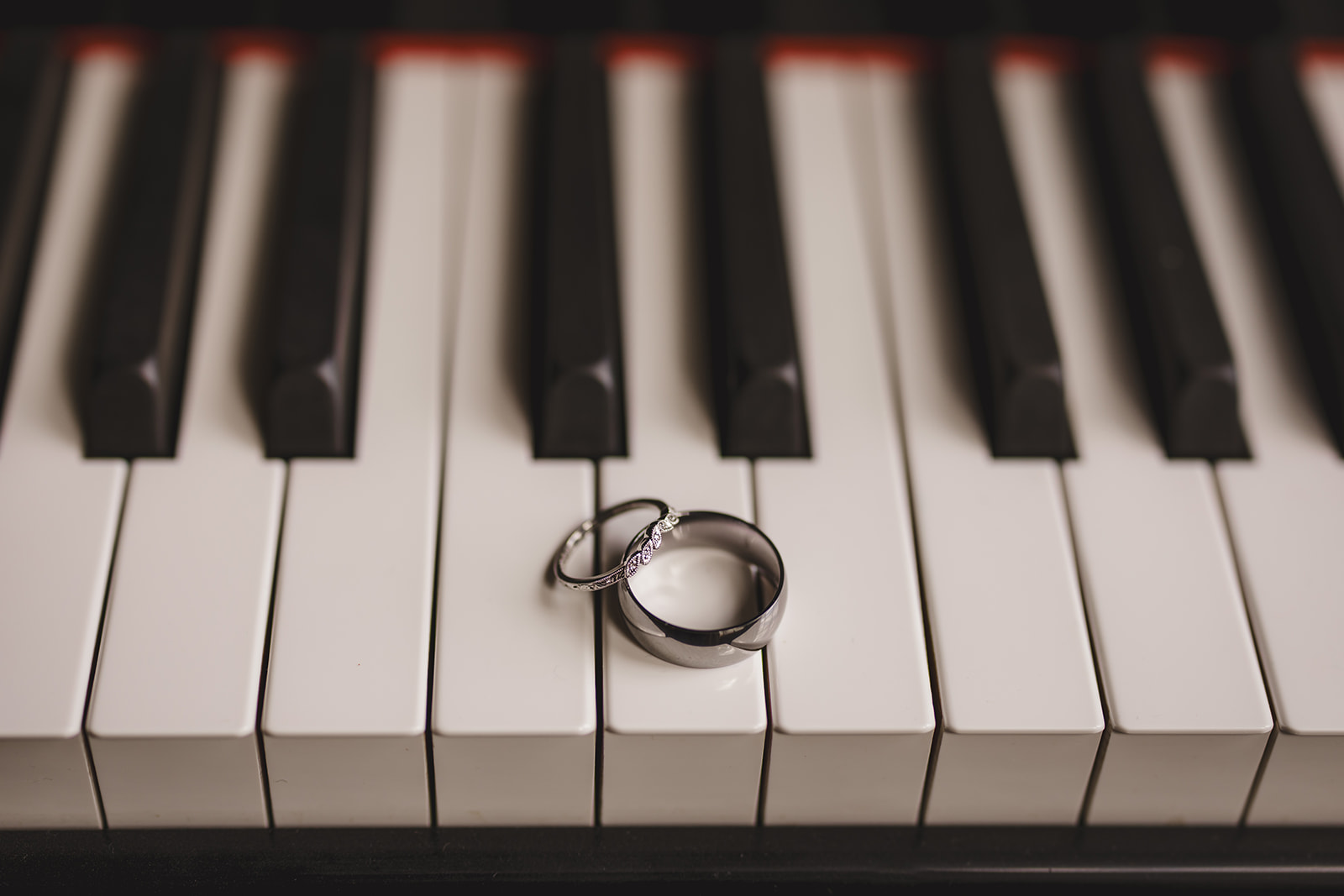 a close up of wedding rings on piano keys
