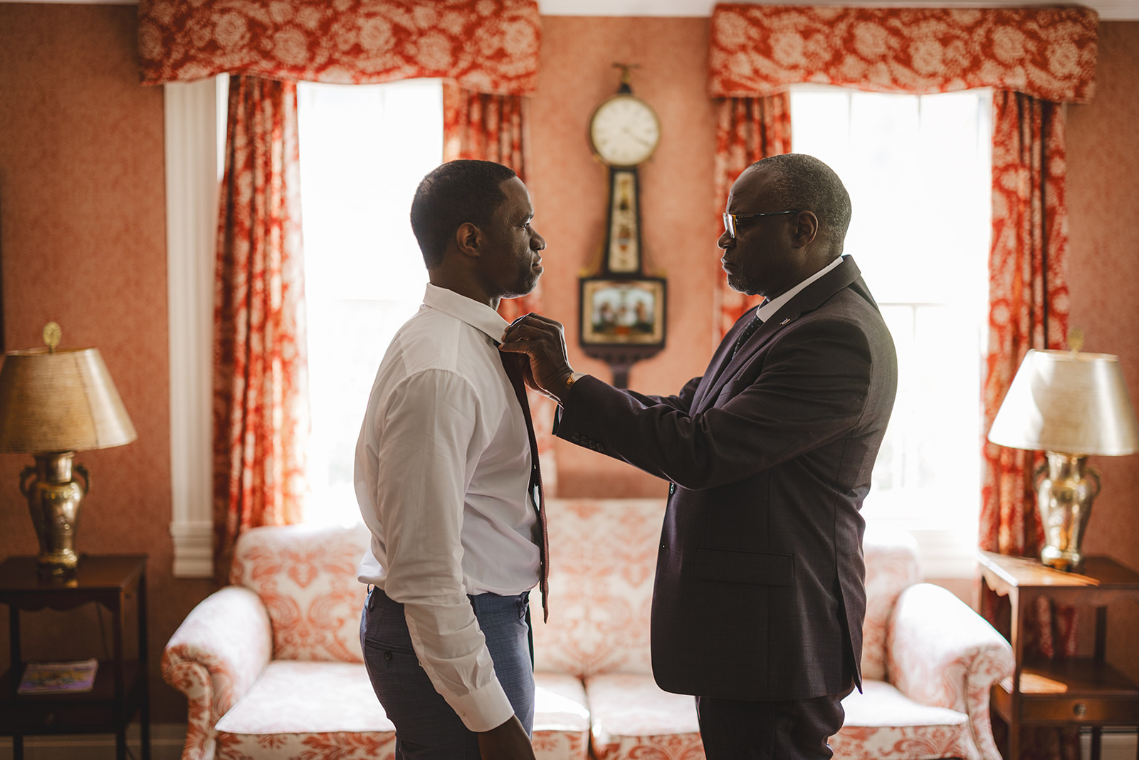 groom's father helps his son get ready for wedding by tying his tie