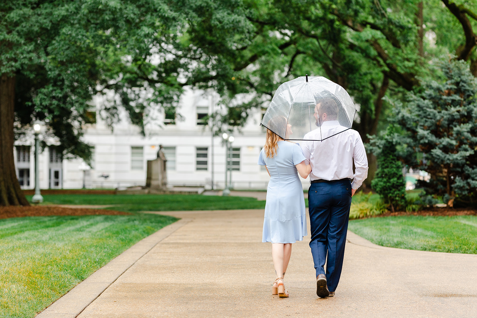 Couple walking in Downtown Raleigh with clear umbrellas in the rain
