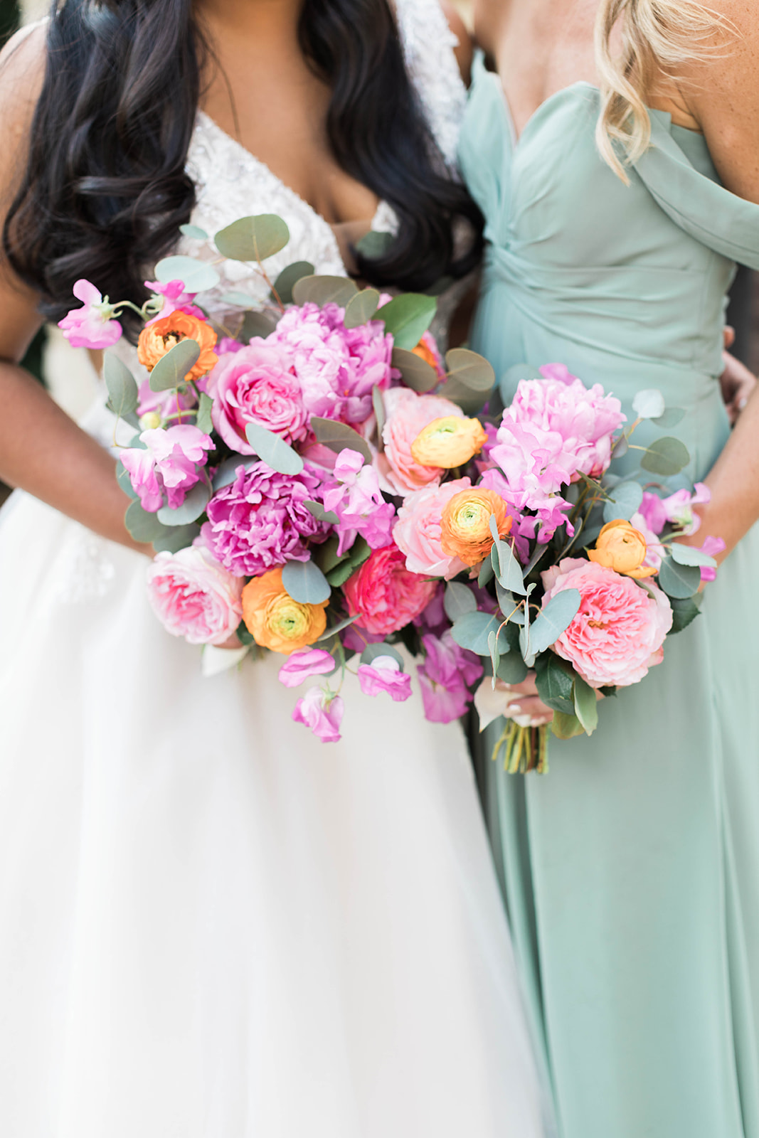 A bride and bridesmaid bouquets with bright pink, green, and orange in the spring