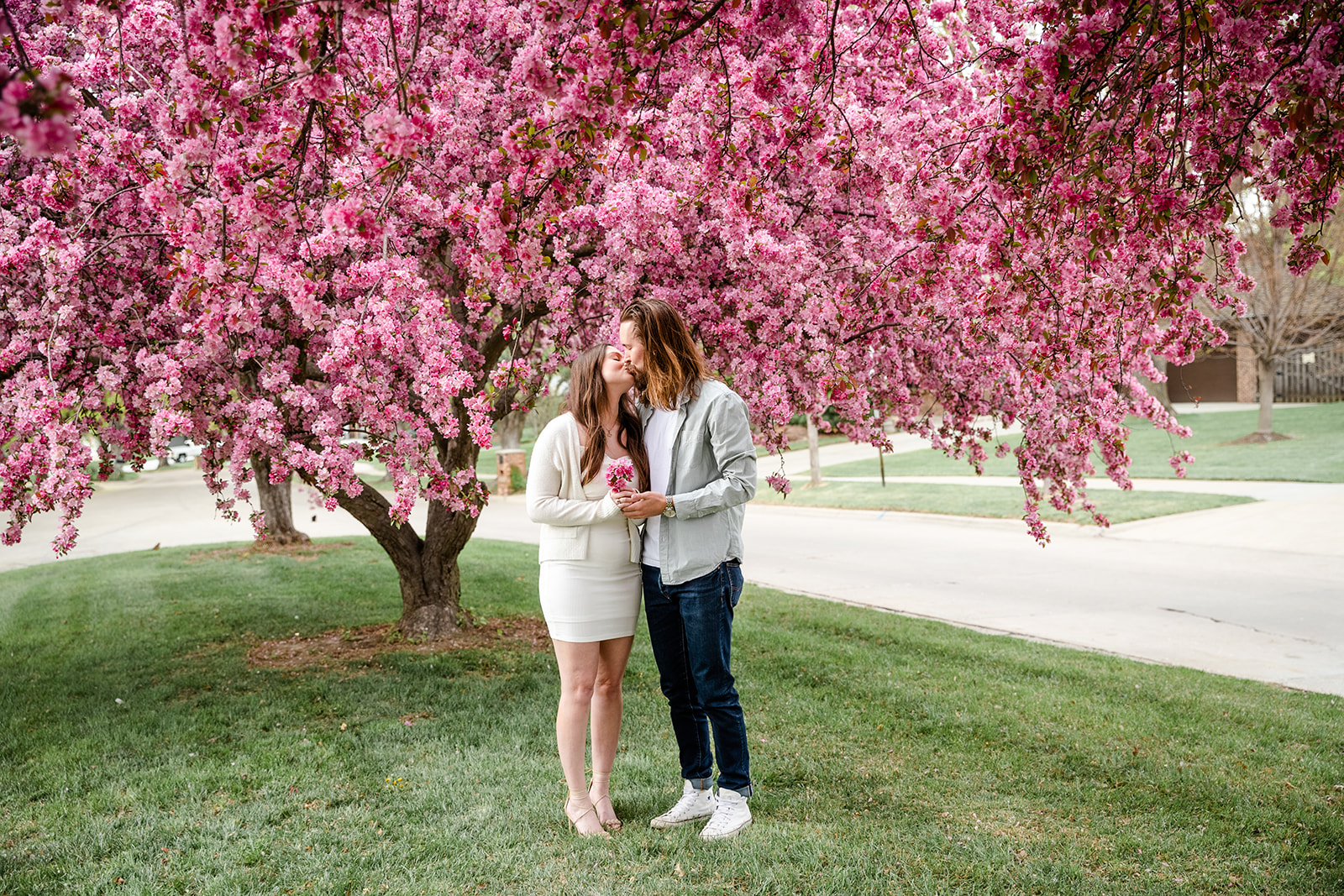 Couple kissing during engagement shoot with purple tree