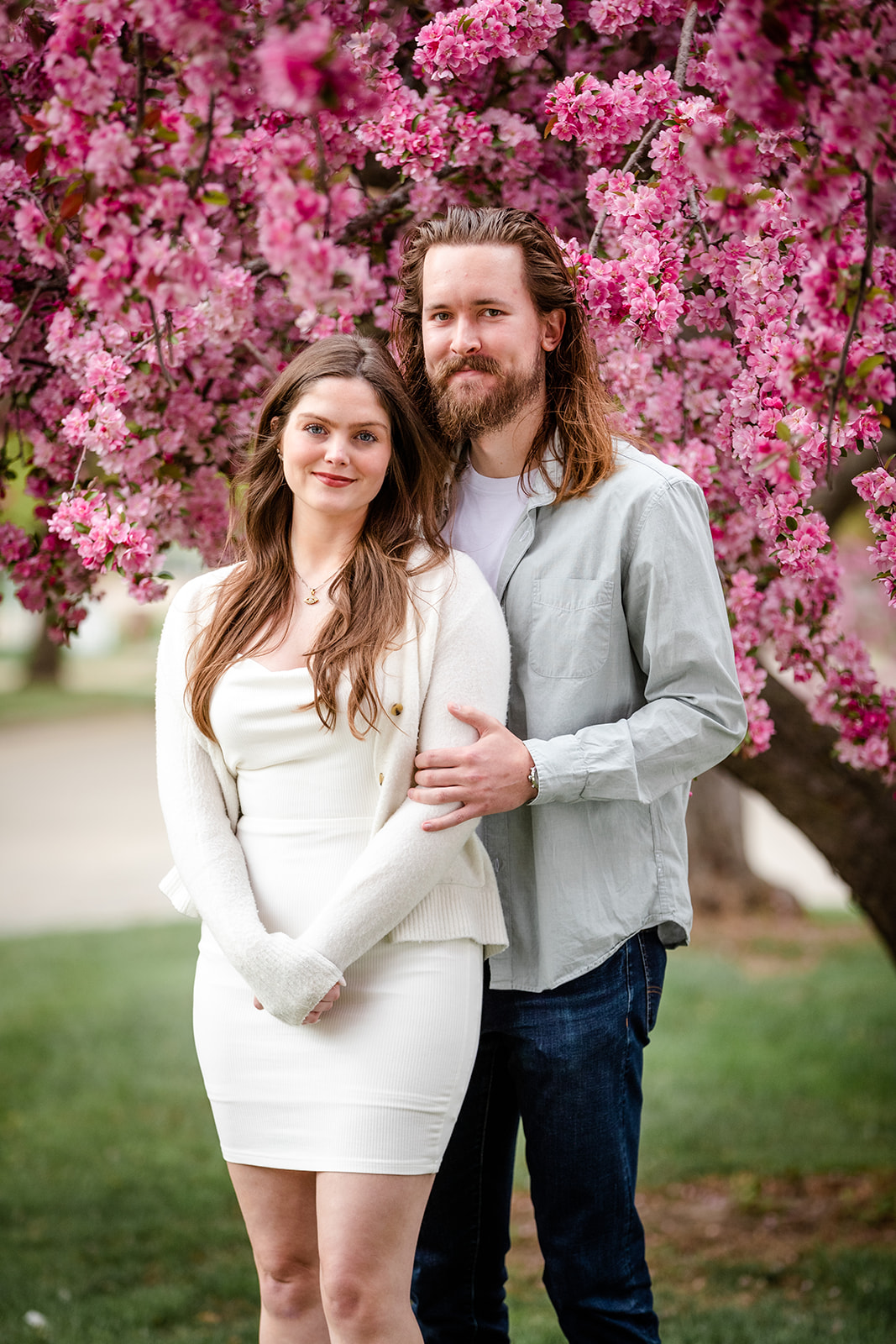 Couple posing in front of a blooming tree