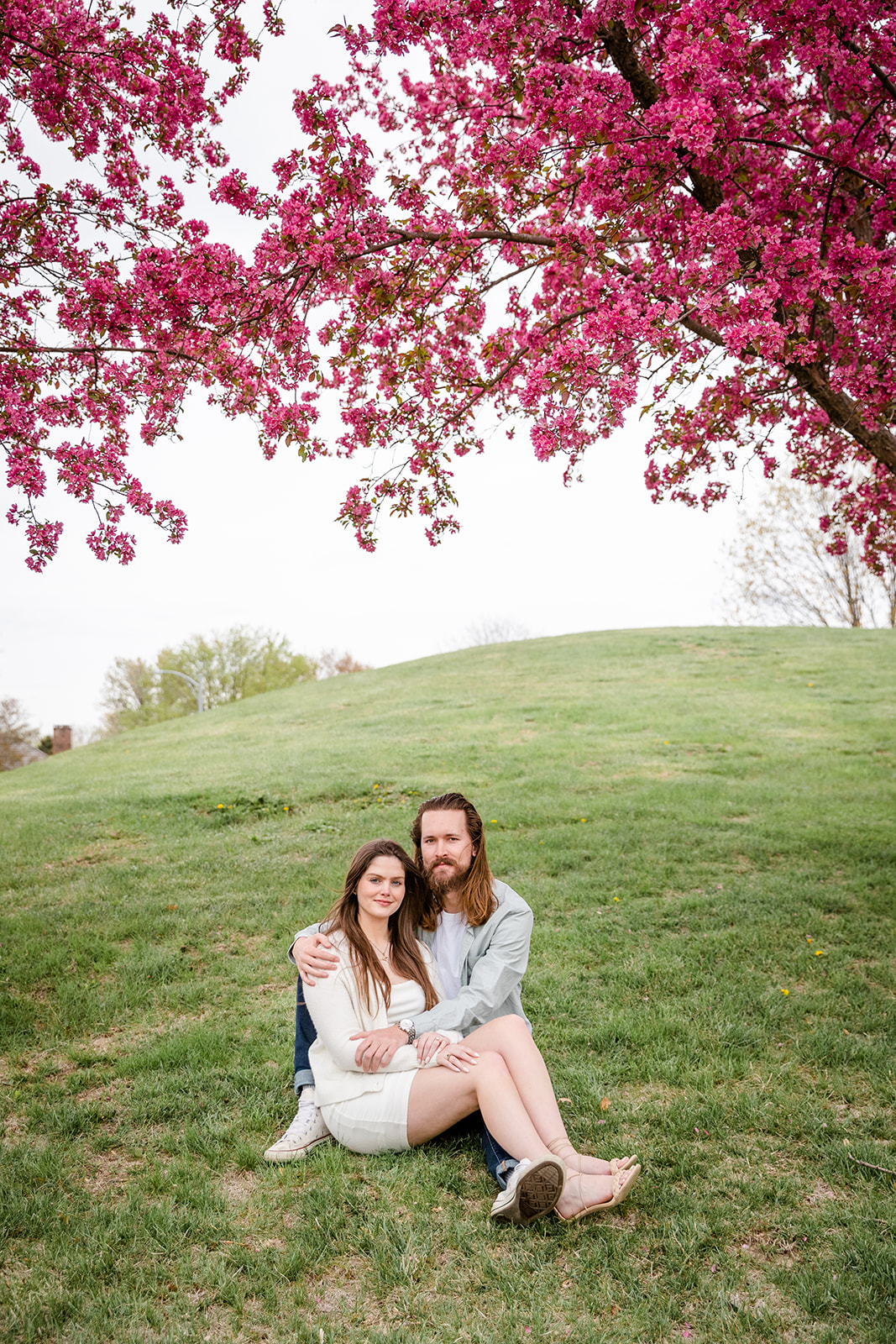Couple sitting on a hill under a tree