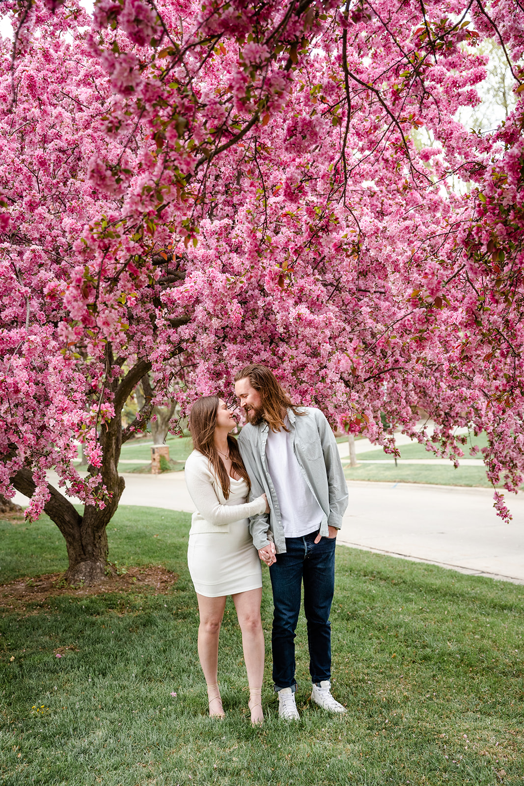 Full body crop of couple kissing by blooming tree