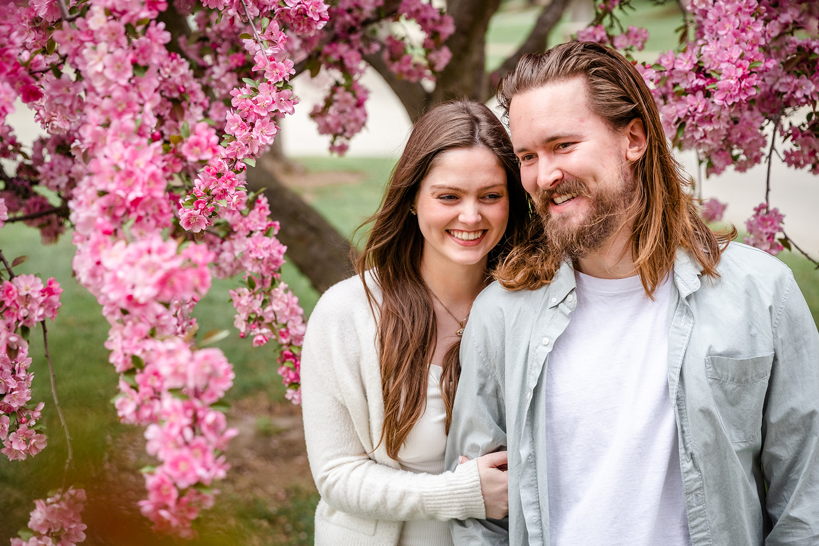 Women looking over shoulder of man during engagement shoot with man laughing