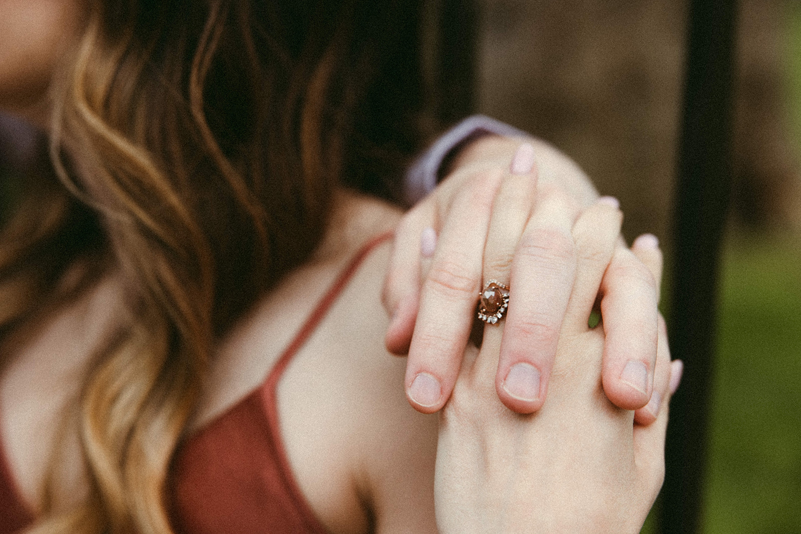 A detail shot of an engaged couple's hand showcasing a woman's brown sapphire engagement ring. 