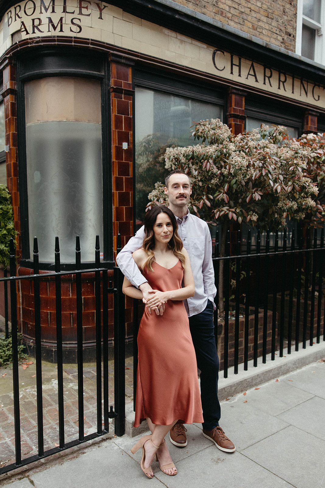 A city couple embraces in front of Charrington's Fine Ales And Stout during their old money aesthetic engagement session