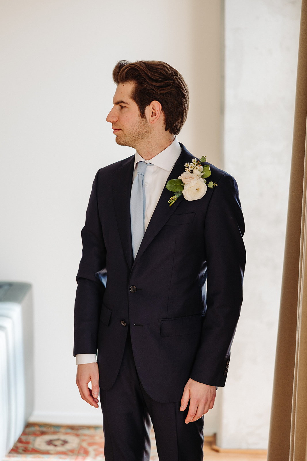 Groom dressed in a suit with a blue tie and white flower 