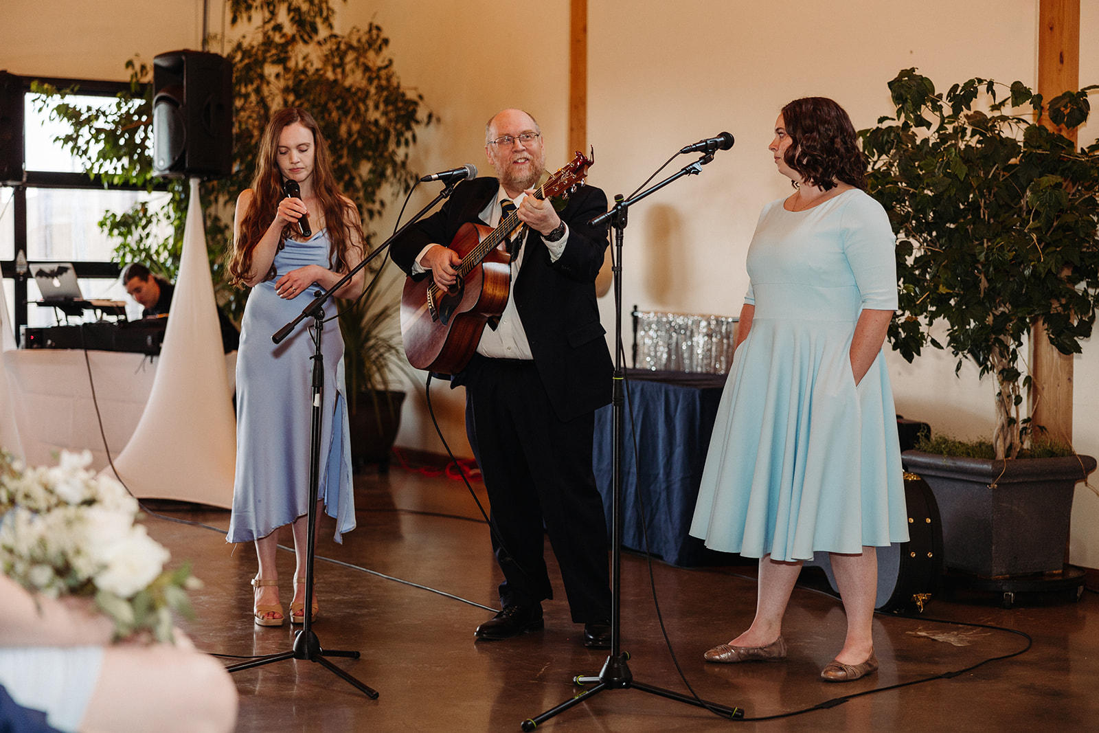 Man playing guitar while women sing during wedding ceremony at Balisteri Vineyards