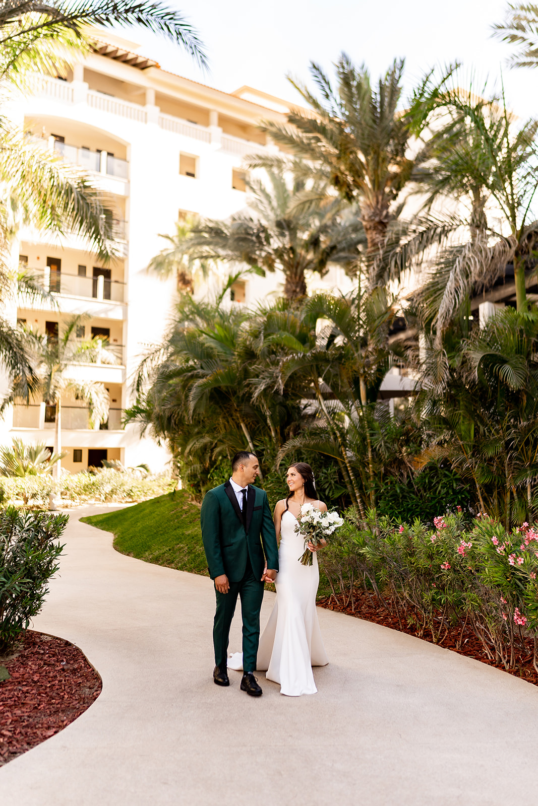 hyatt ziva los cabos bride and groom walking at resort under palm trees