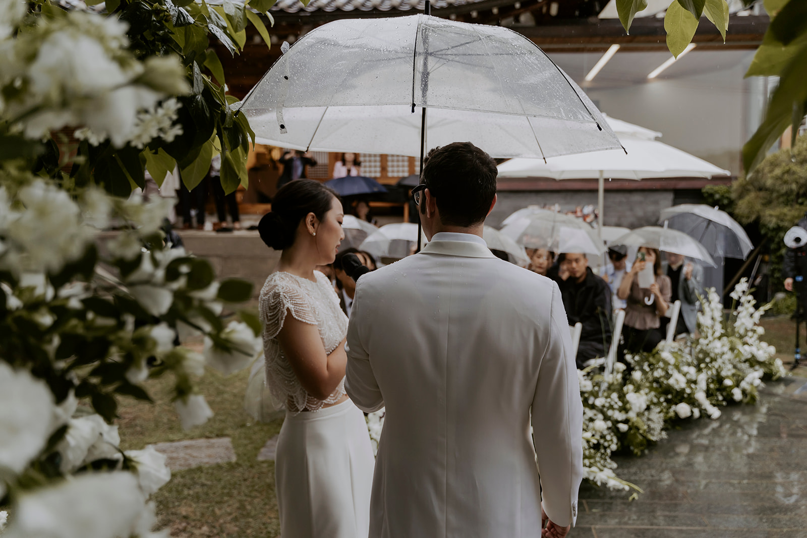 A bride and groom standing under an umbrella.