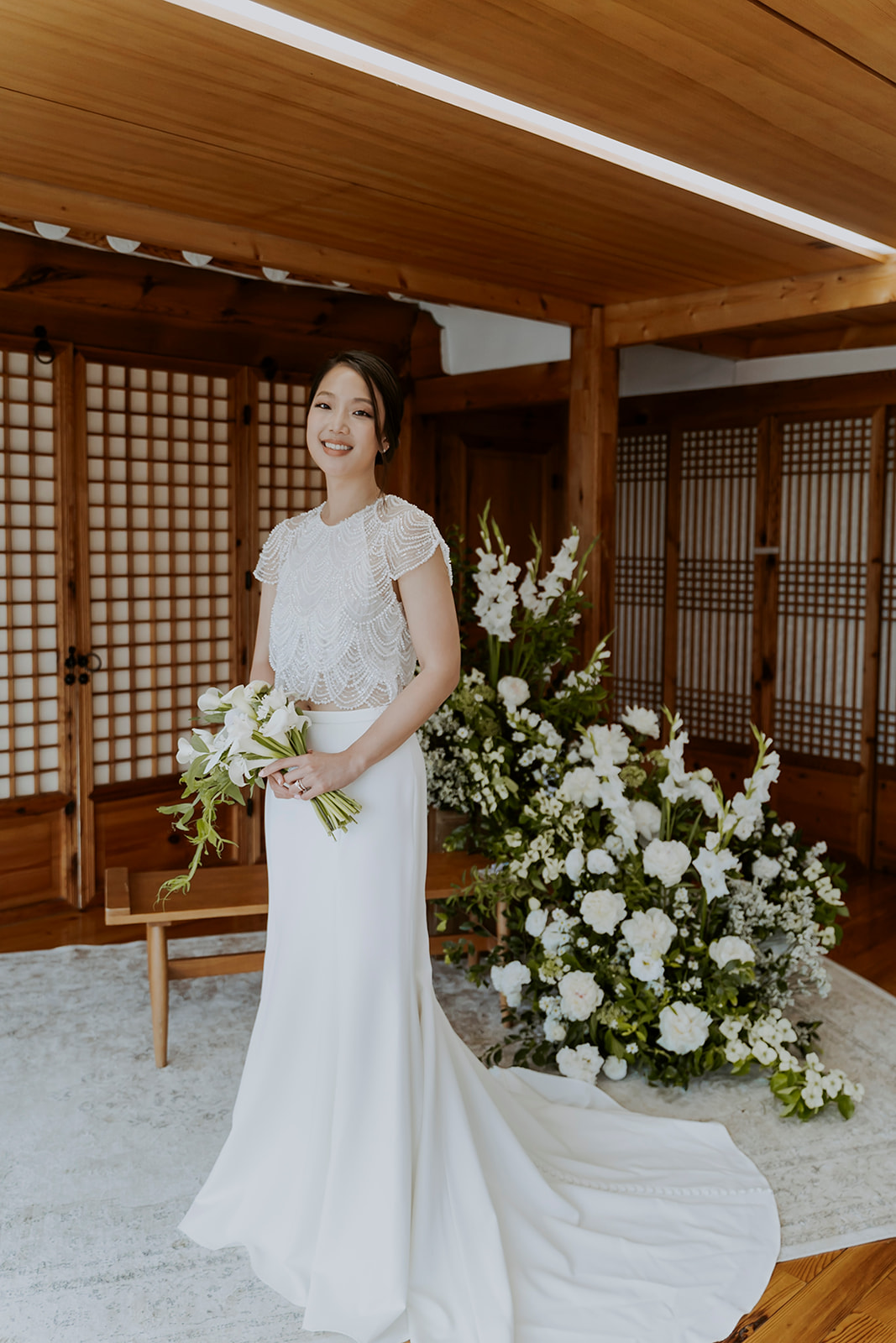 A bride in a white wedding dress standing in a wooden room.
