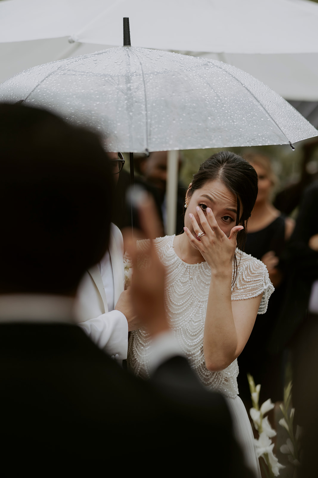 A hanok bride is crying while holding an umbrella in the rain.