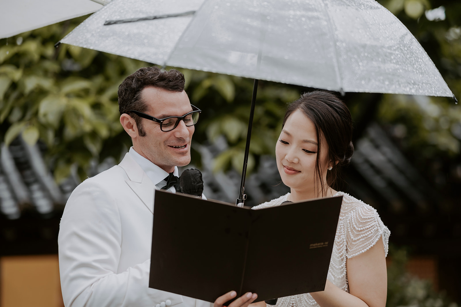 A hanok wedding ceremony where the bride and groom exchange heartfelt vows under a beautifully decorated umbrella.