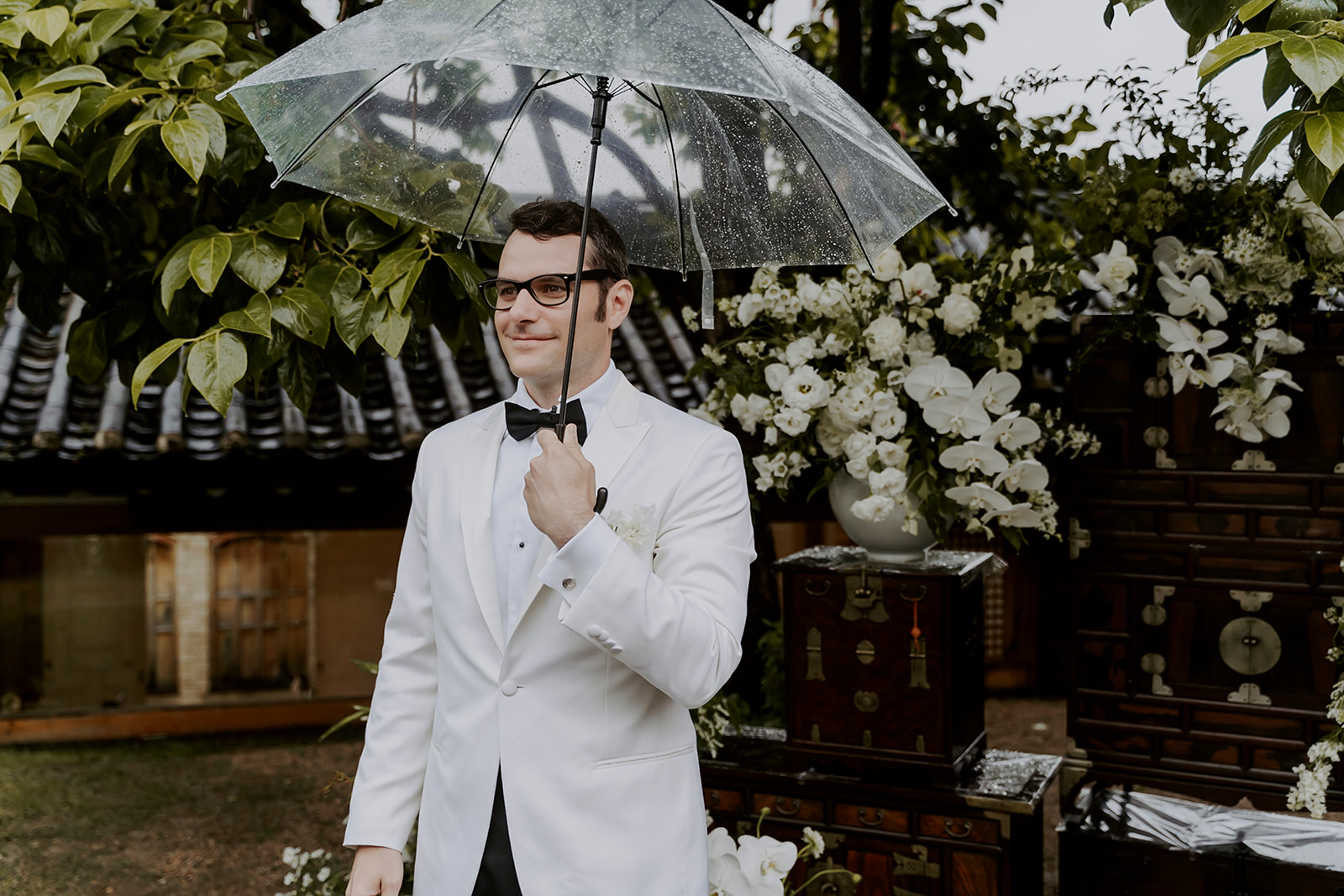 The groom waiting for the bride standing and holding an umbrella. 