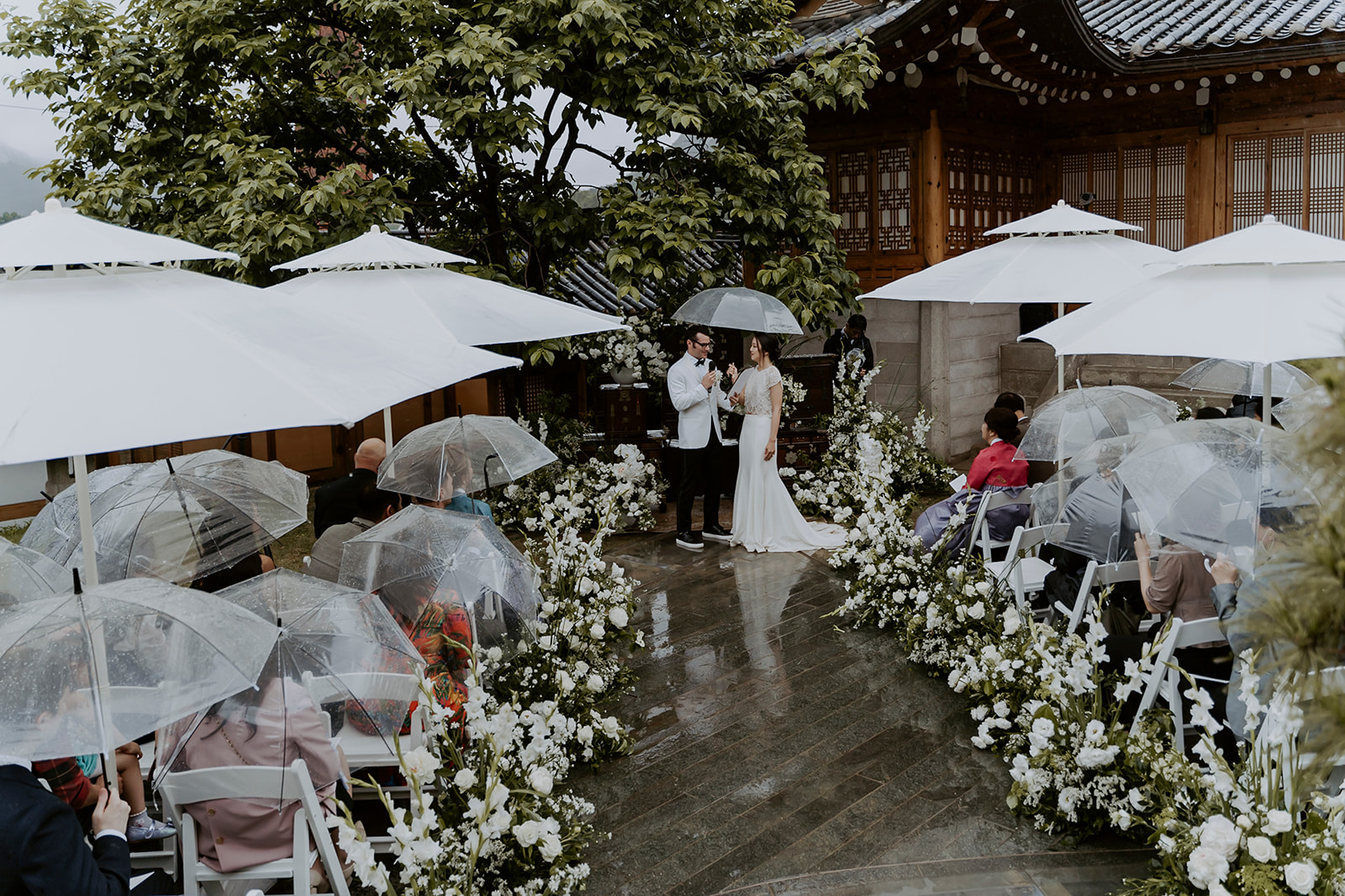 A wedding ceremony under umbrellas in the rain.