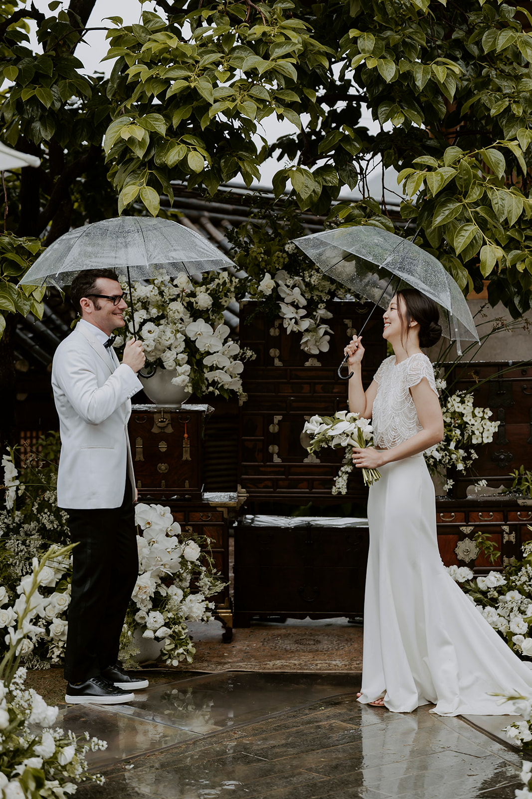 A wedding couple saying their vows under umbrellas in the rain during a South Korean ceremony.
