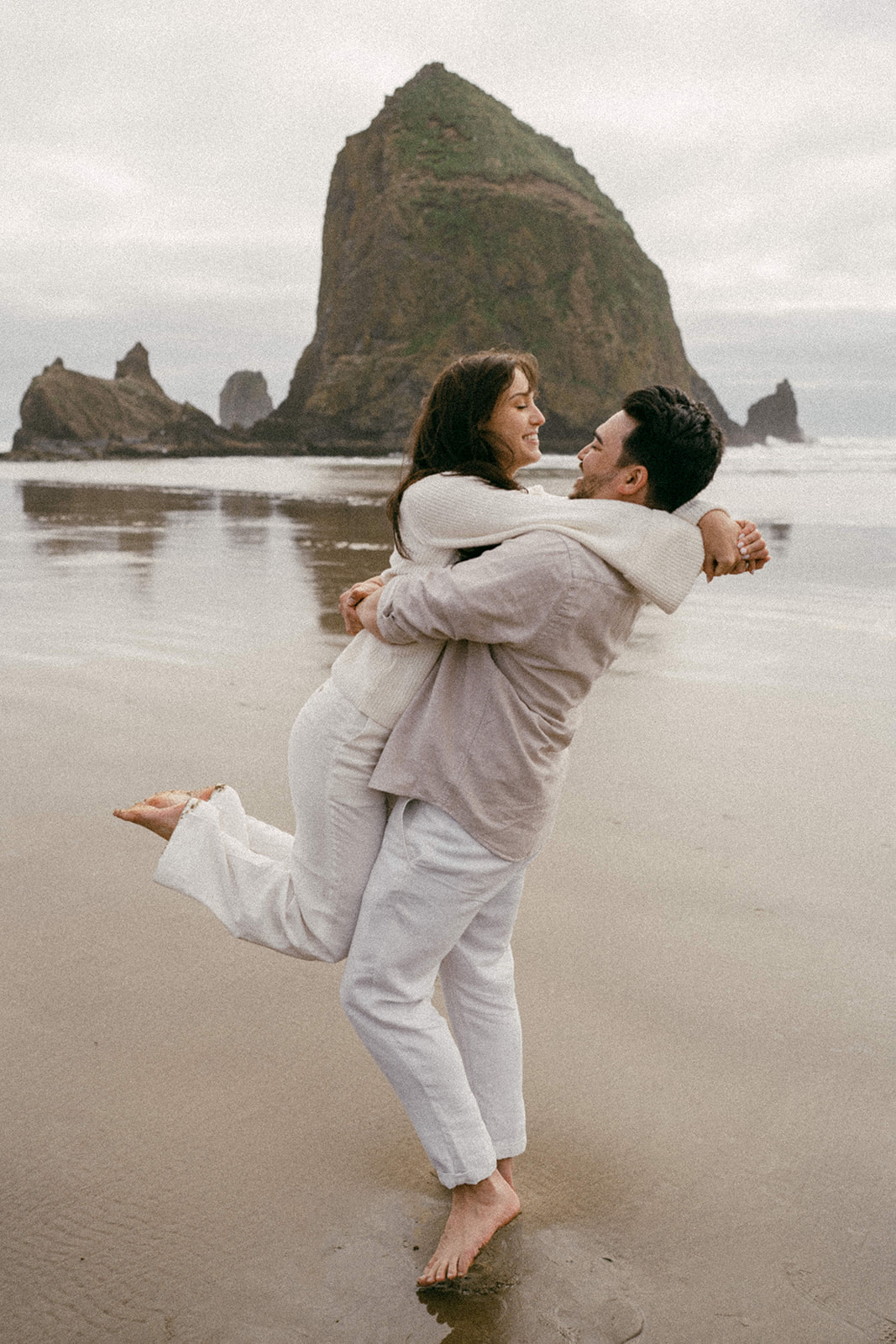 A couple at their engagement session in front of Haystack Rock at Cannon Beach on the Oregon Coast shot on film