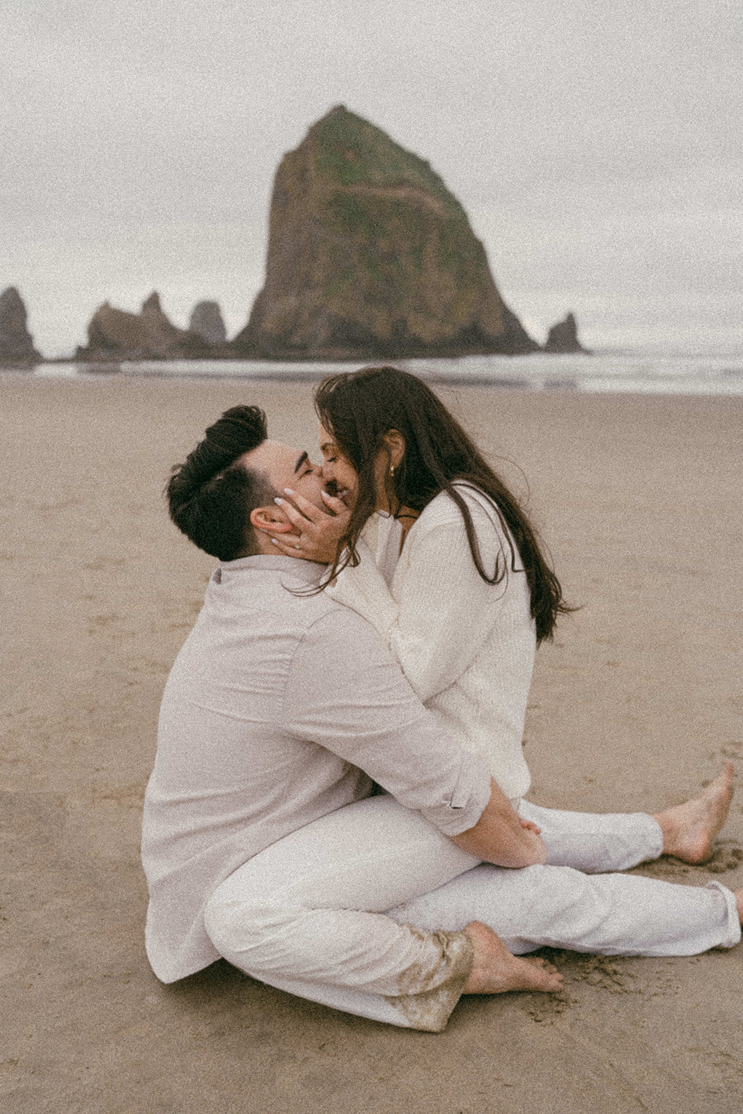 A couple at their engagement session in front of Haystack Rock at Cannon Beach on the Oregon Coast shot on film