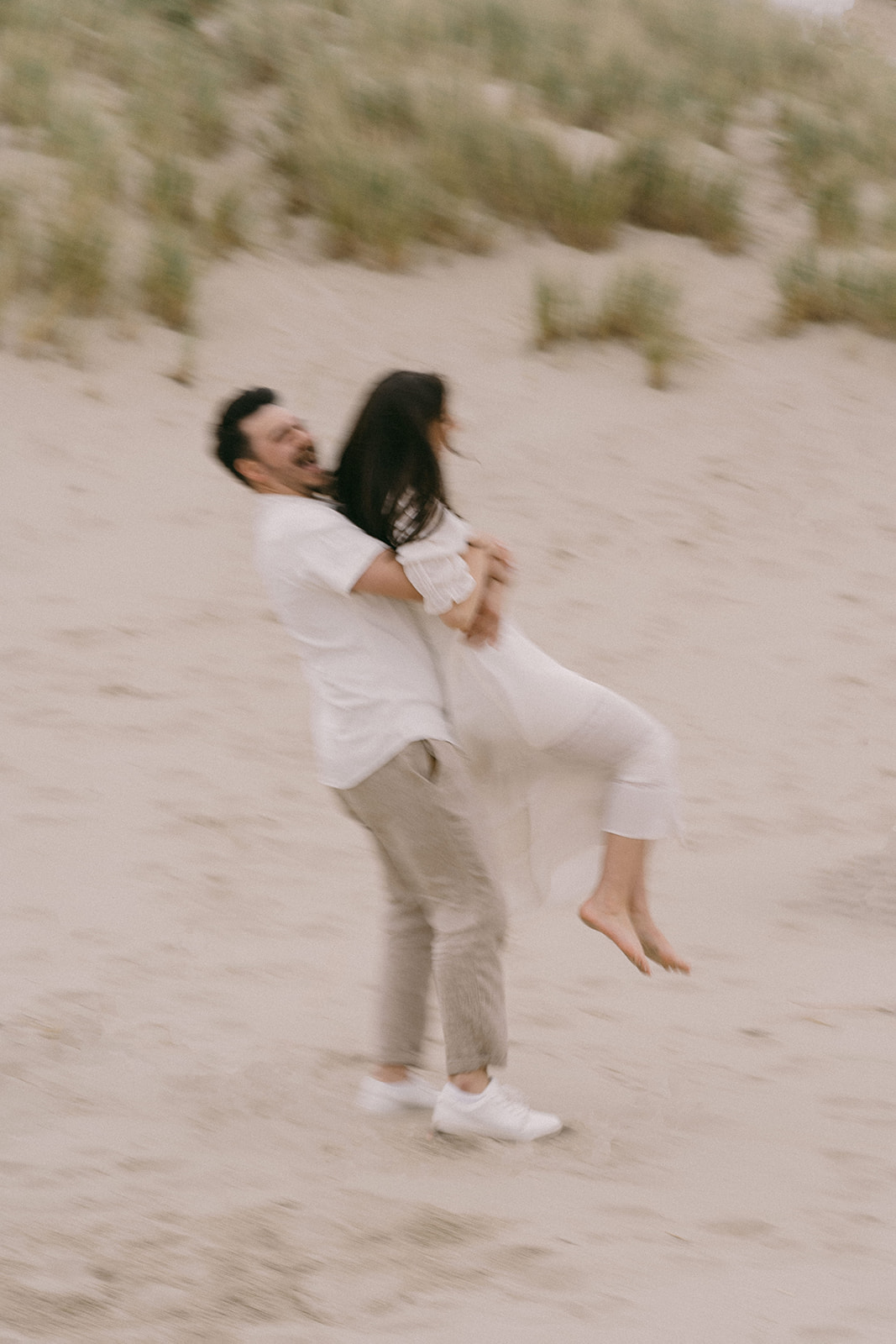 A couple wearing white at their engagement session in Cannon Beach Oregon shot in film style