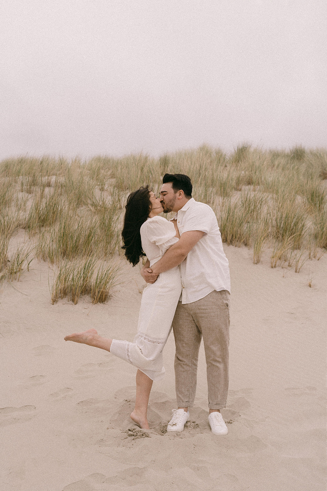 A couple wearing white at their engagement session in Cannon Beach Oregon shot on film