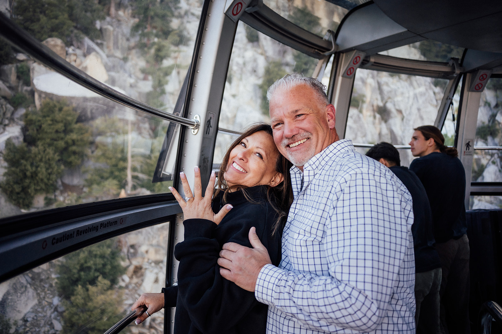 Woman showing off engagement ring with man hugging her in Tram on Mount San Jacinto near Palm Springs California.