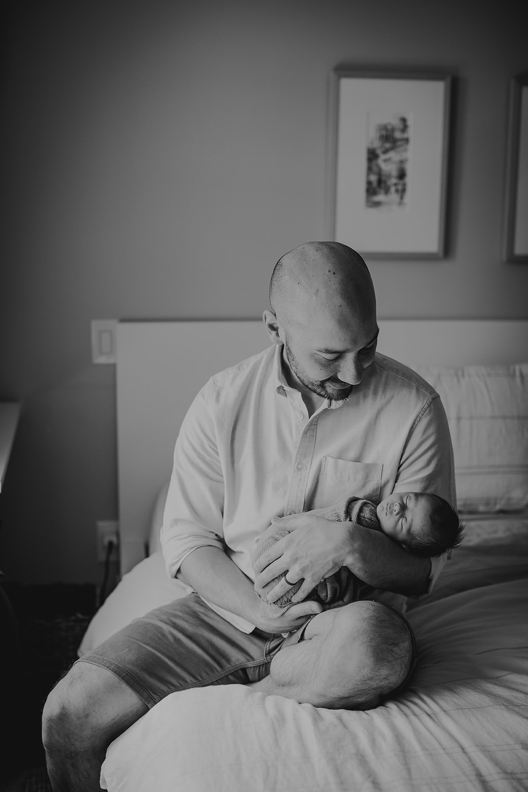 a black and white photography of a  father looking down proudly at his newborn son