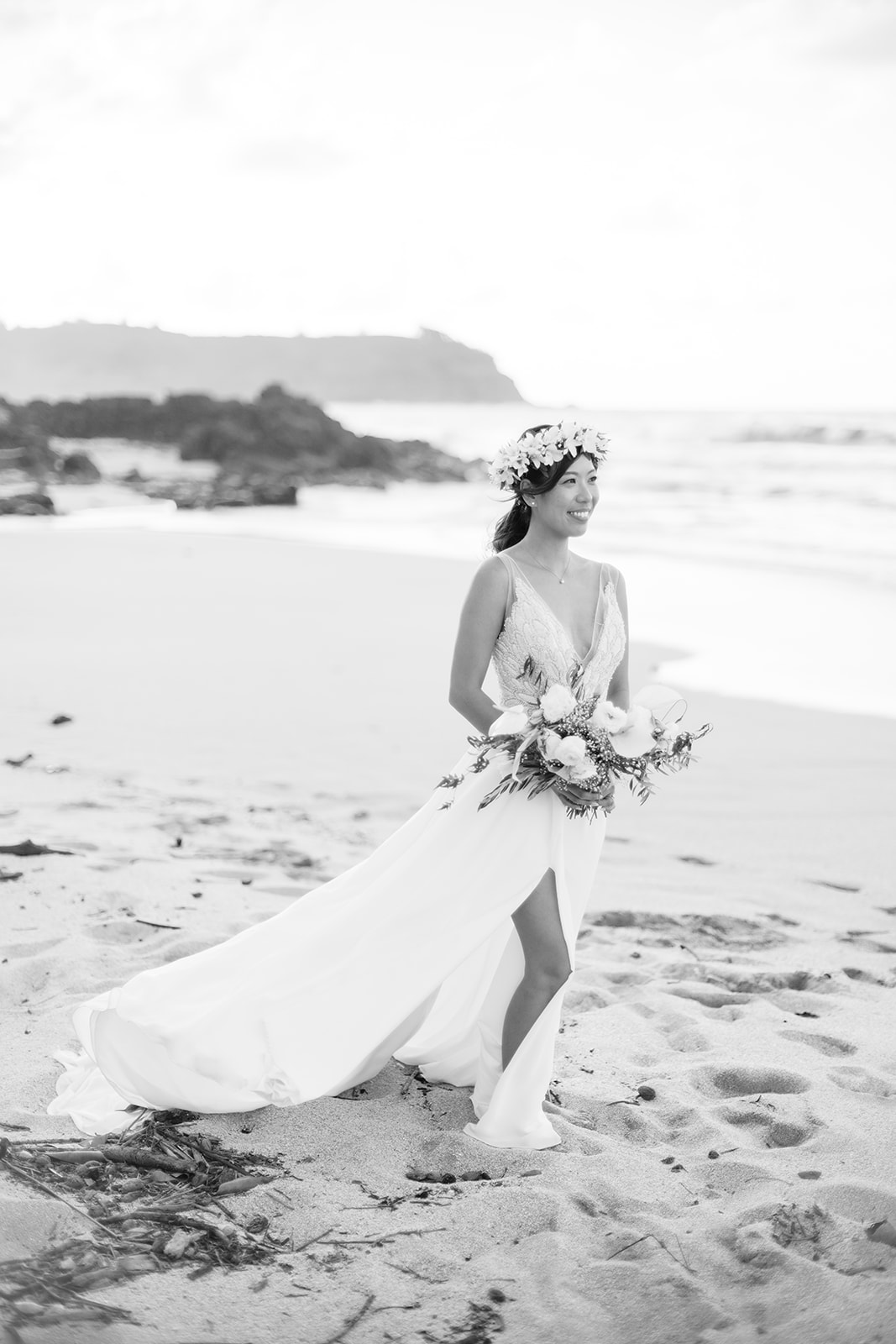 black and white photo of a bride in flowing white dress holding a bouquet, on a beach wedding in Oahu