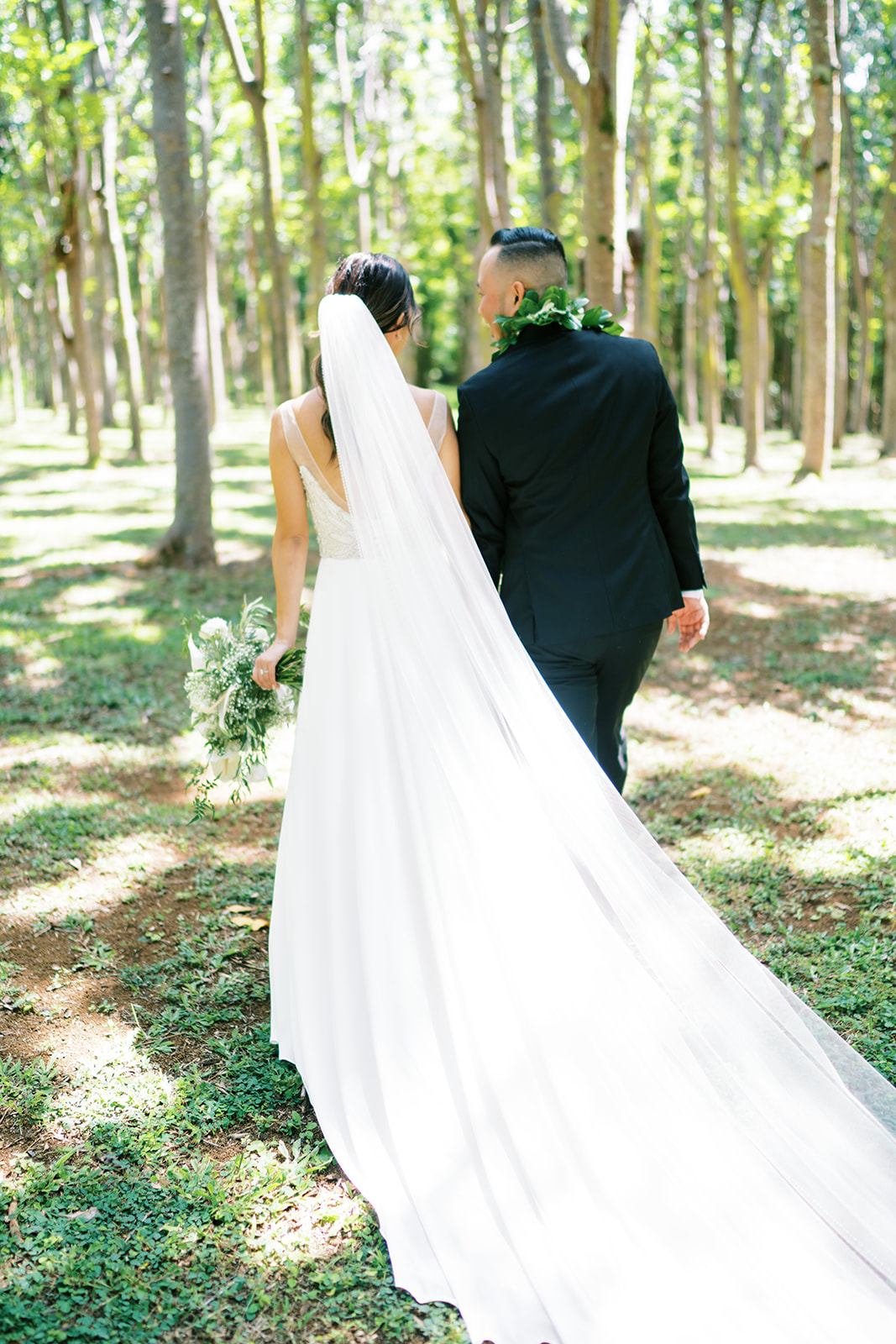 Bride and groom walking hand in hand through a forest captured by Oahu Wedding Photographer Megan Moura