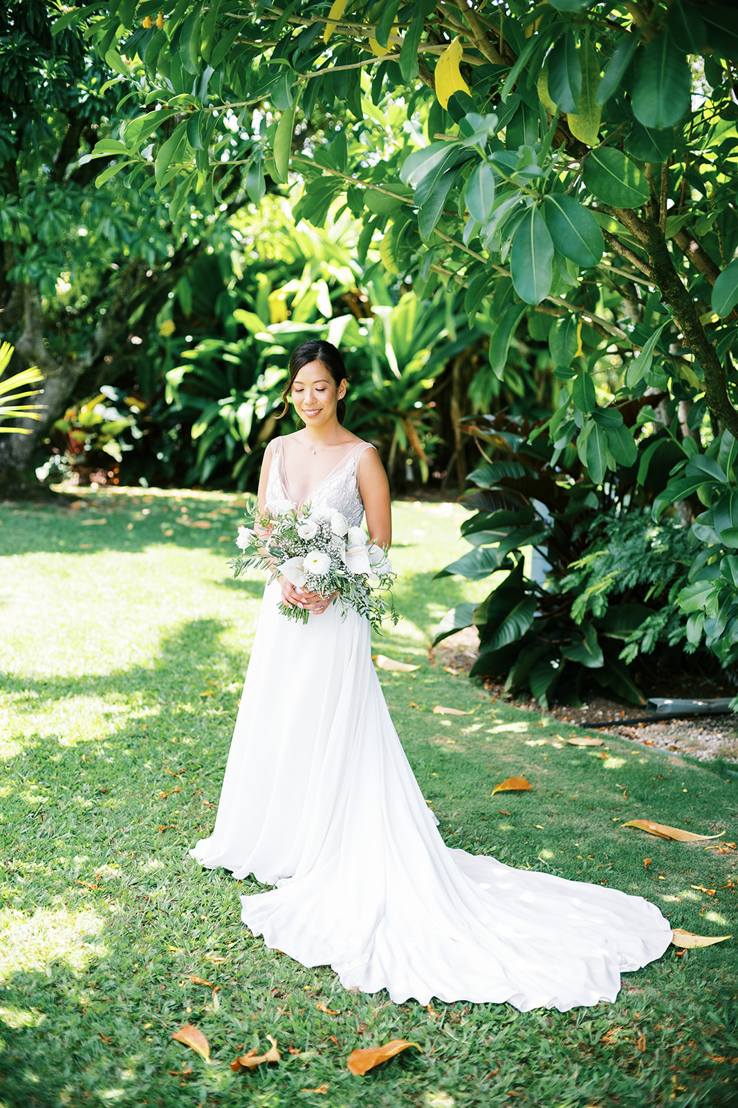 Bride standing in a garden, holding a bouquet captured by Oahu Wedding Photographer Megan Moura