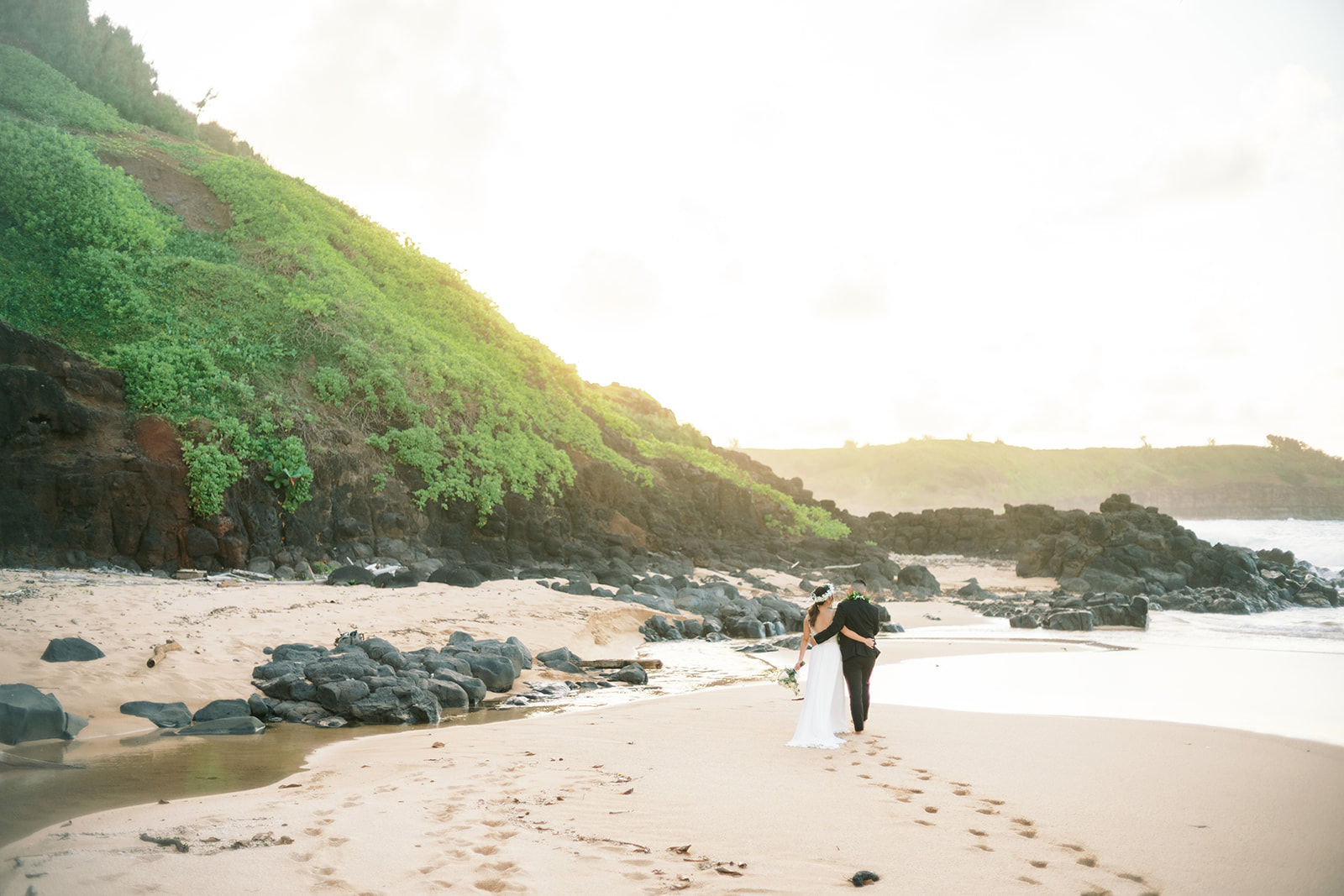 Couple sharing an intimate moment on a serene beach at sunset in Na Aina Kai captured by Oahu Wedding Photographer